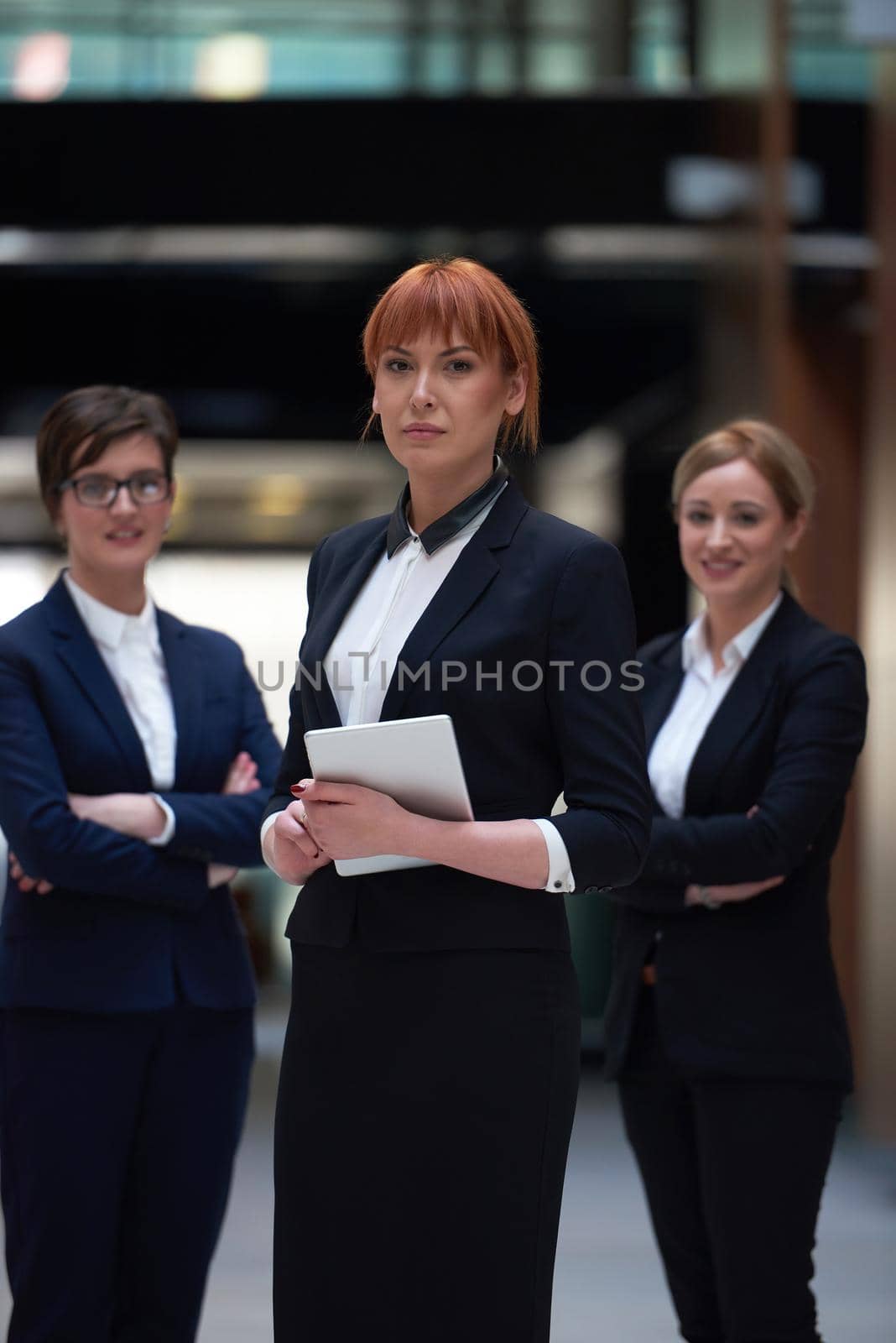 young business woman group,  team standing in modern bright office and working on tablet computer