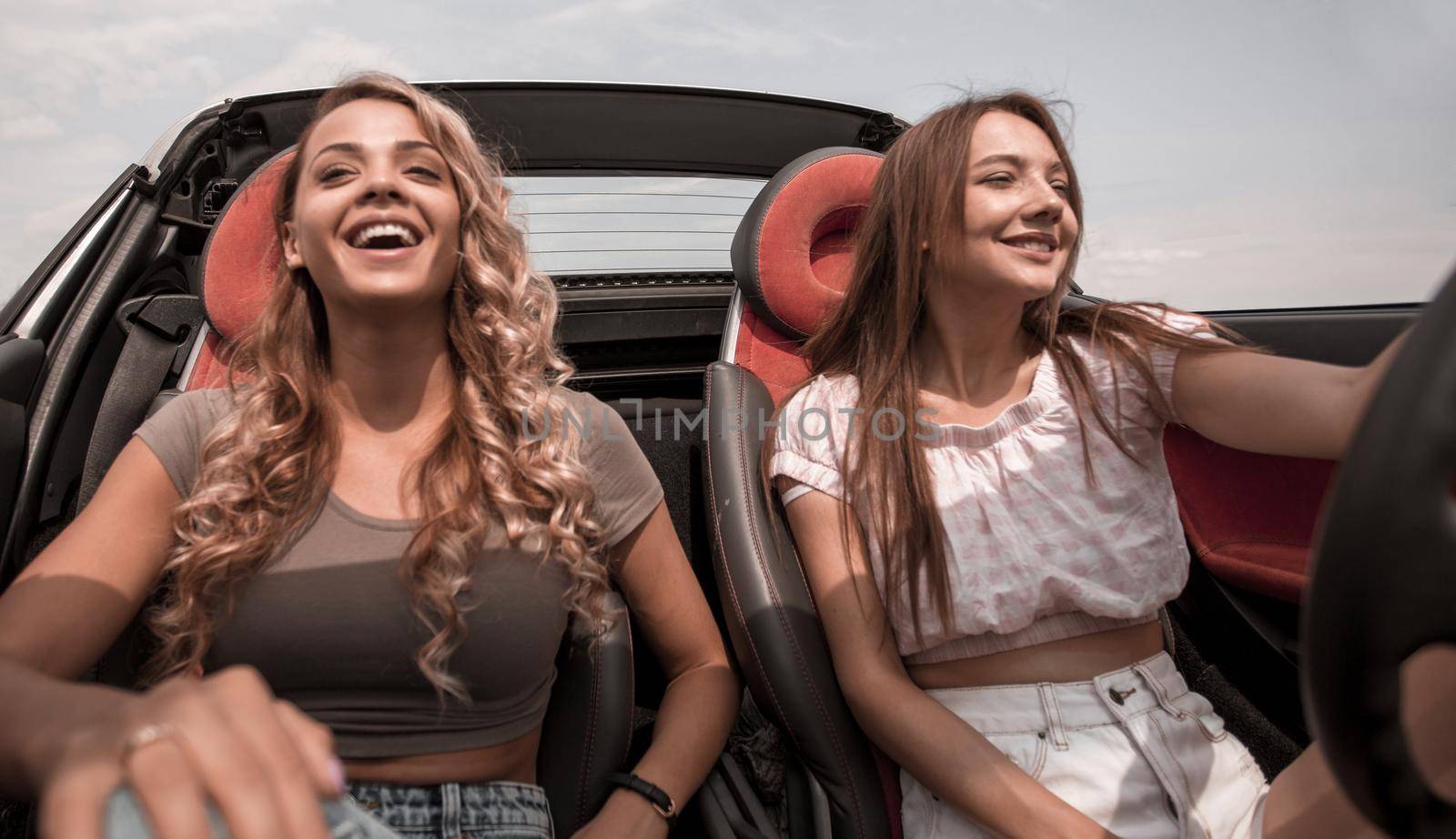 two young women riding in a convertible.leisure, travel, travel and people