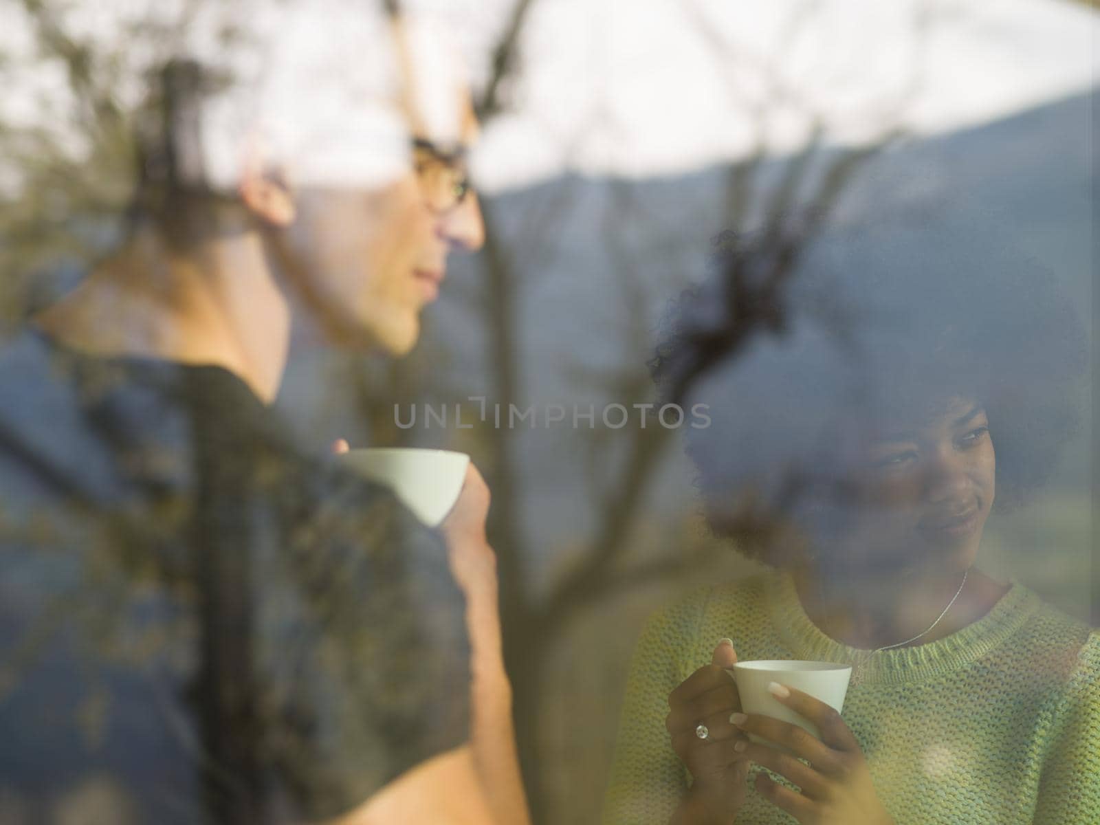 romantic happy young multiethnic couple enjoying morning coffee by the window in their luxury home