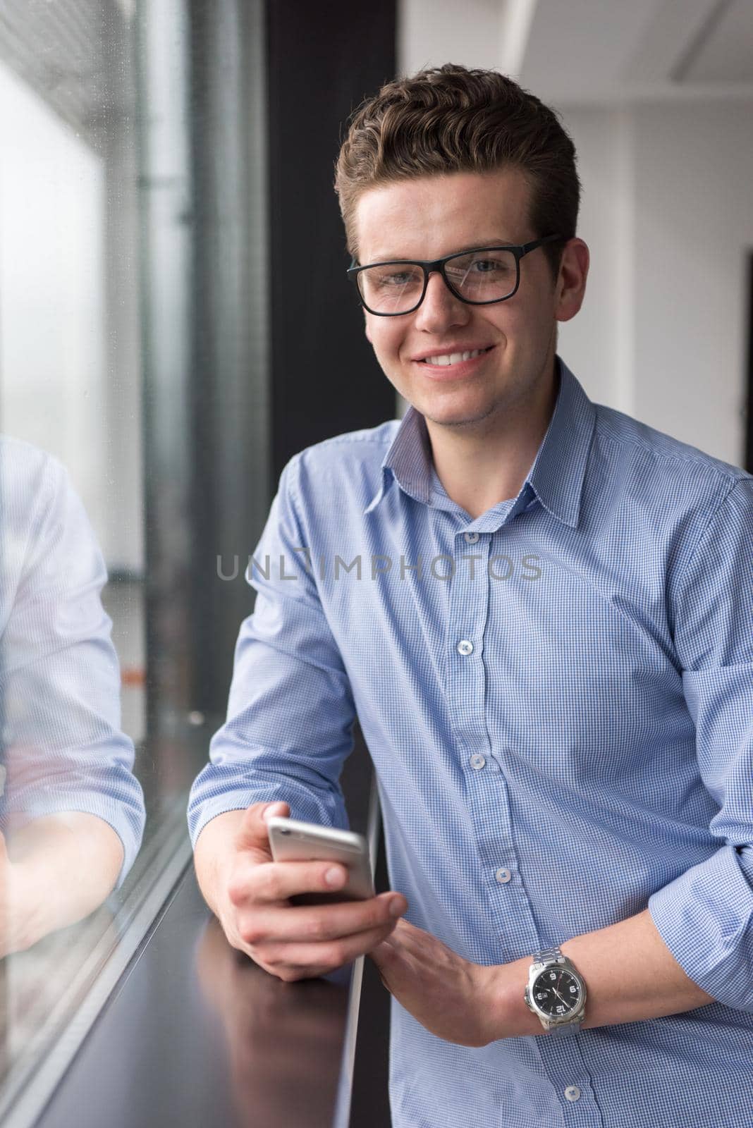 Businessman Standing In A Modern Building Near The Window With Phone by dotshock