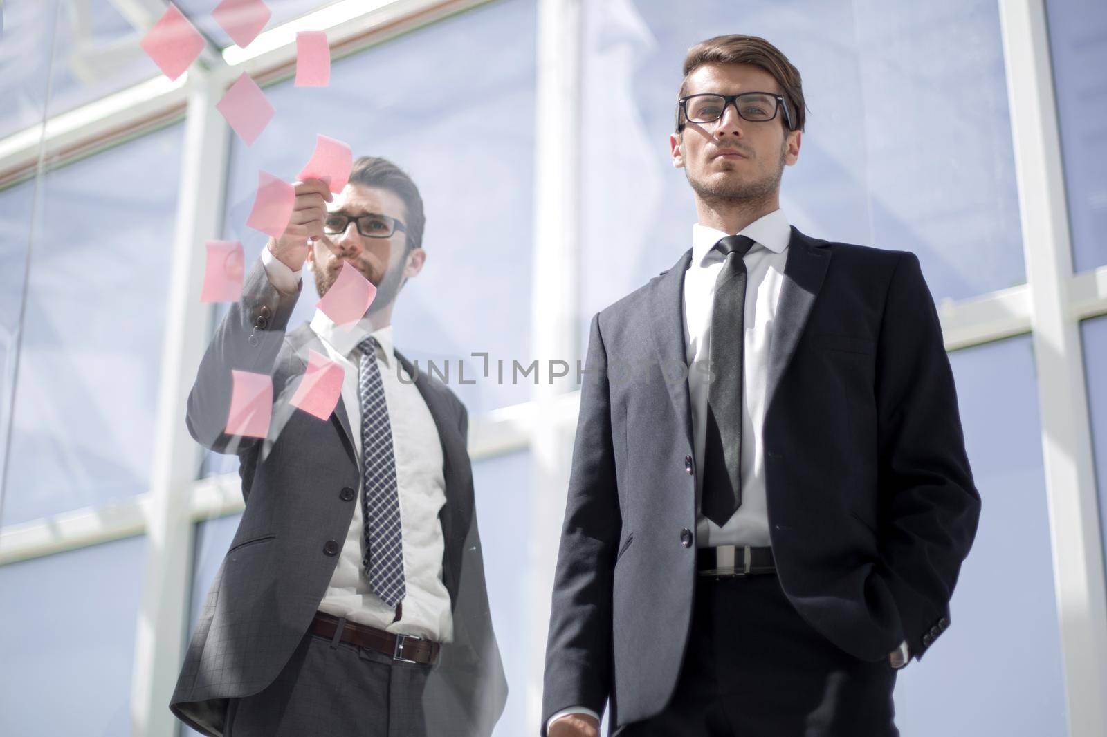 Business colleagues read stickers pasted on a transparent glass wall. business concept