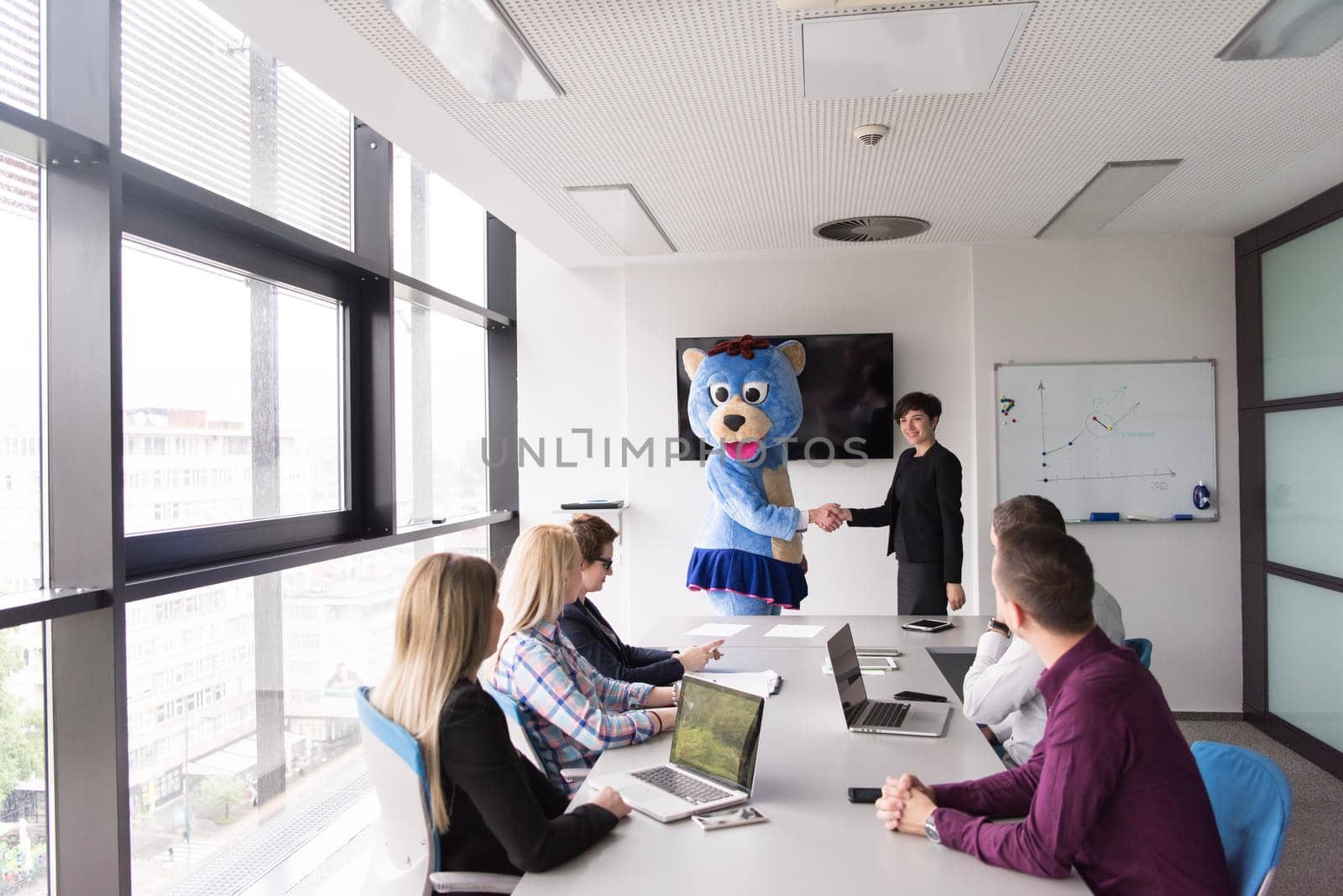 boss dresed as bear having fun with business people in trendy office by dotshock