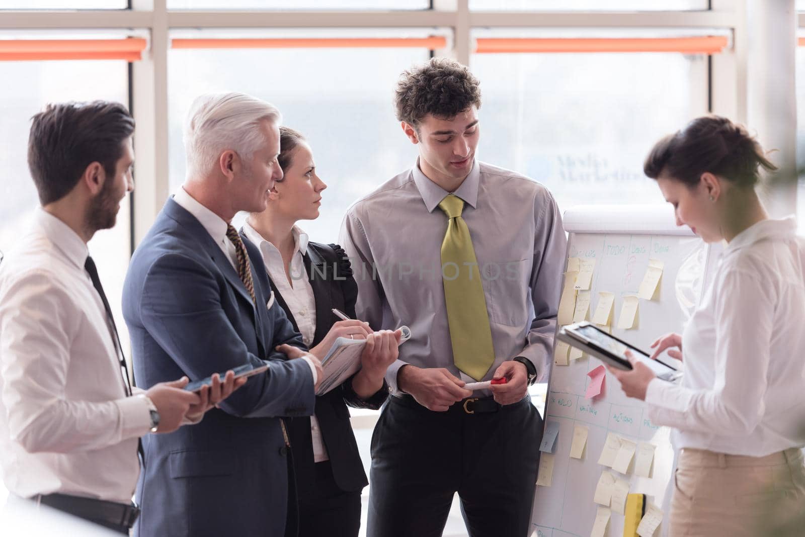 young startup businessman making presentation of project to senior investior, group of business people taking notes and make plans on white  flip board and tablet computer