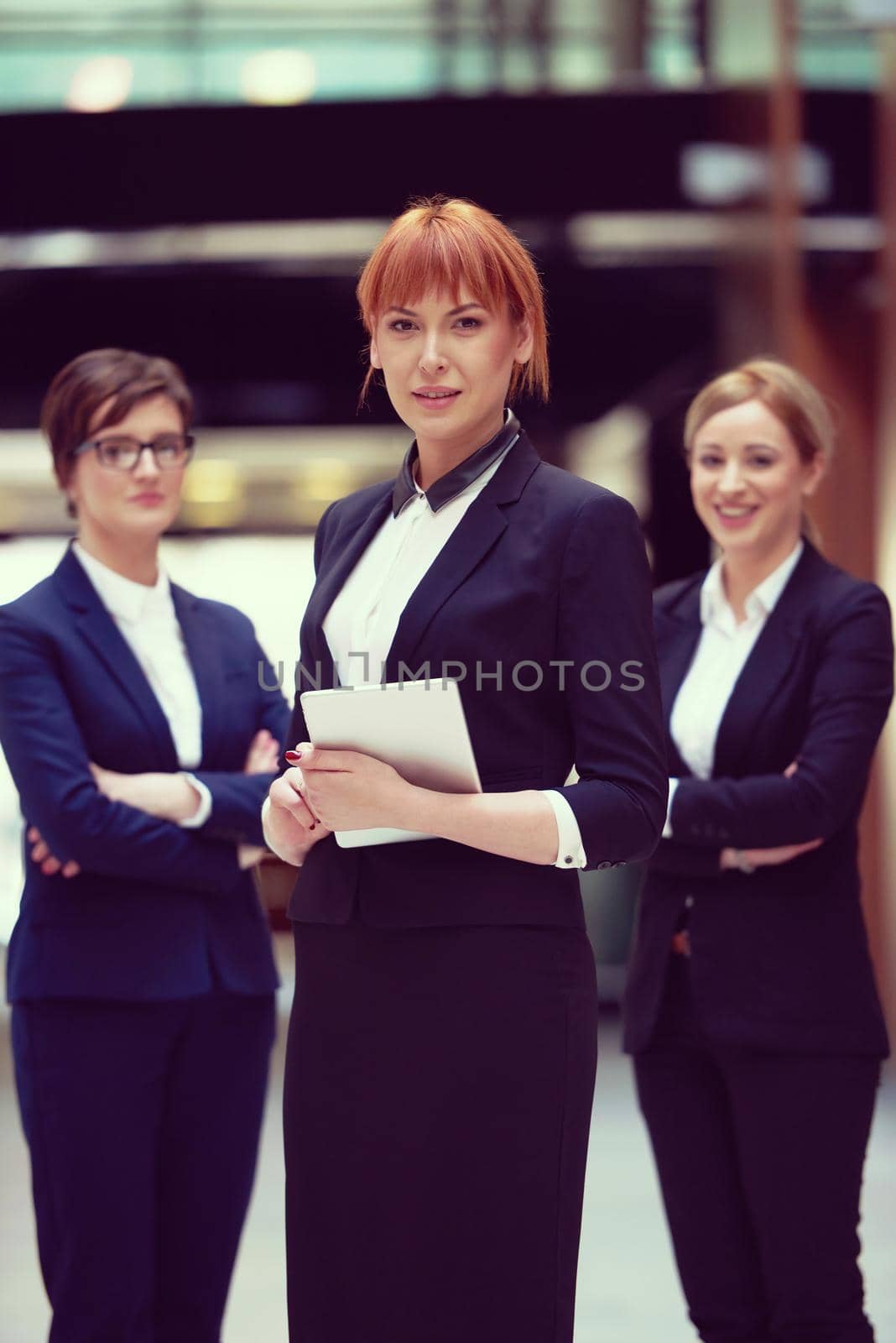 young business woman group,  team standing in modern bright office and working on tablet computer