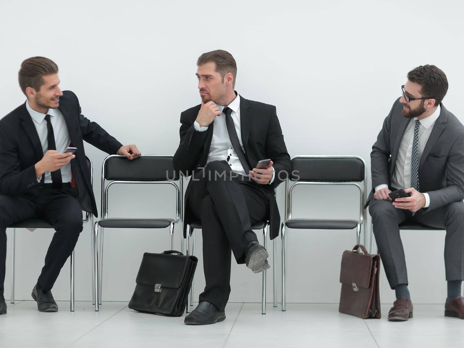 employees with smartphones sitting in the office hallway by asdf