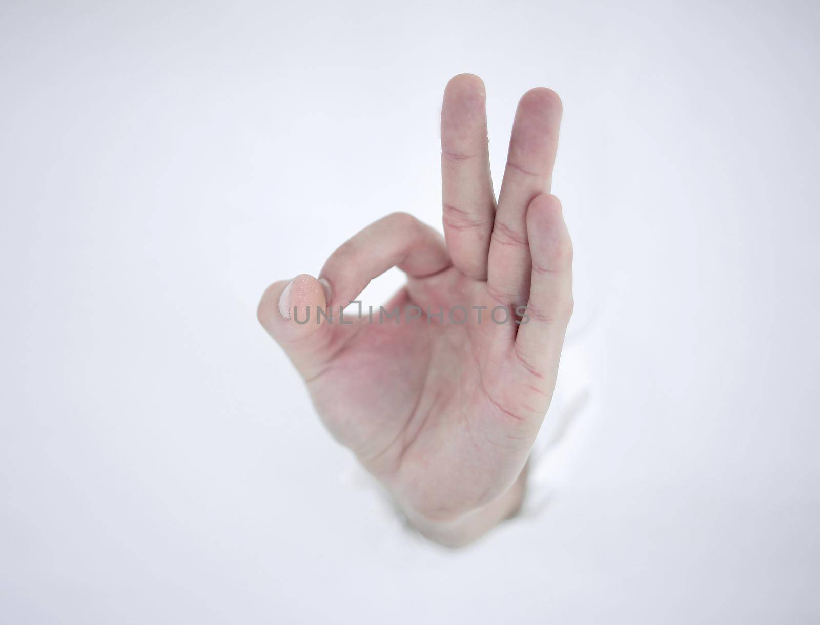 man's hand breaking through the paper wall and pointing at you .photo with copy space