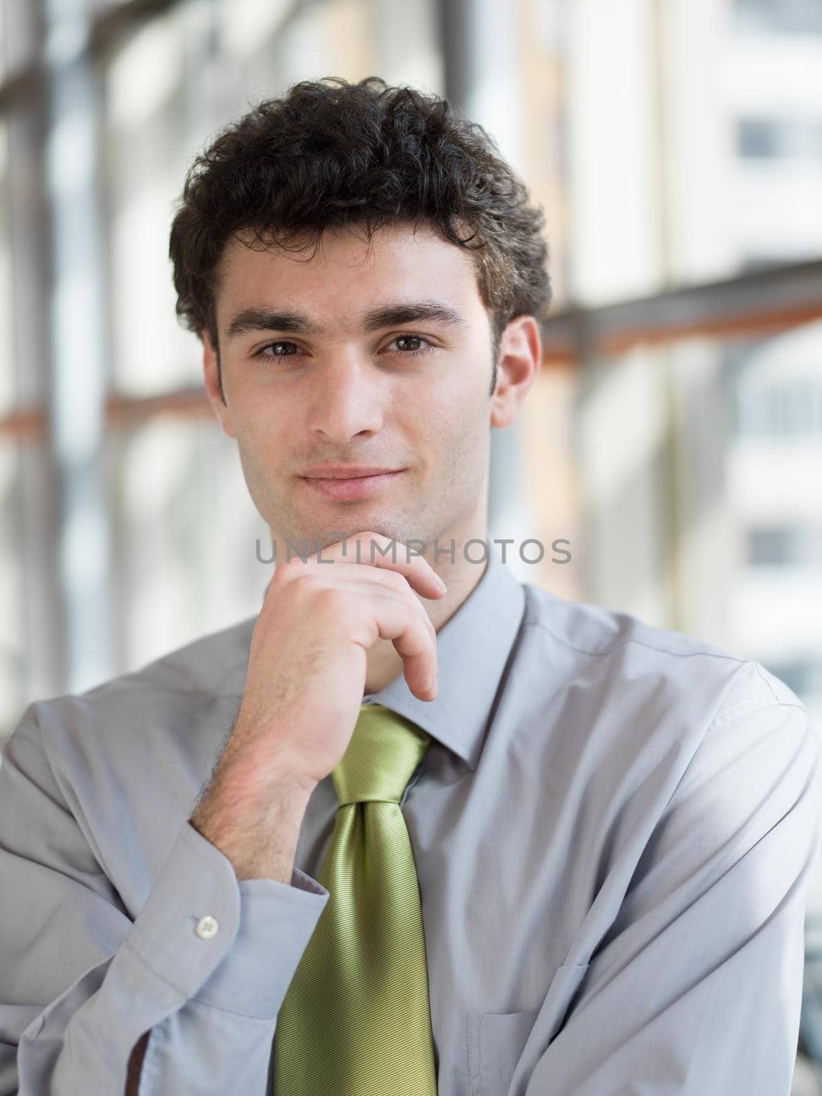 portrait of young business man at modern office  interior with big windows in background