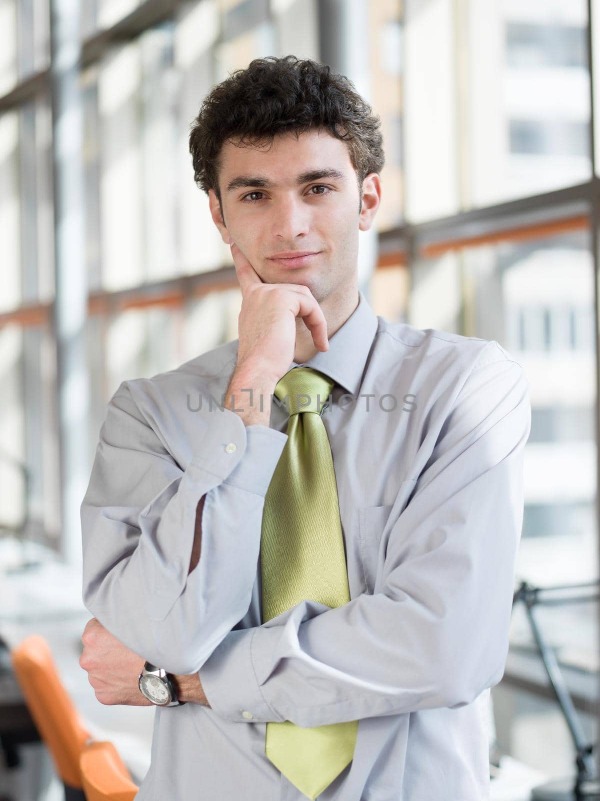 portrait of young business man at modern office  interior with big windows in background