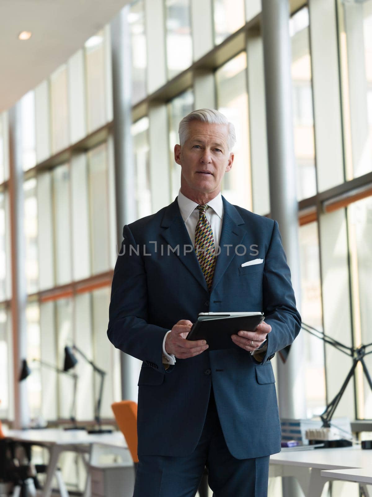 handsome senior business man working on tablet computer at modern bright office interior