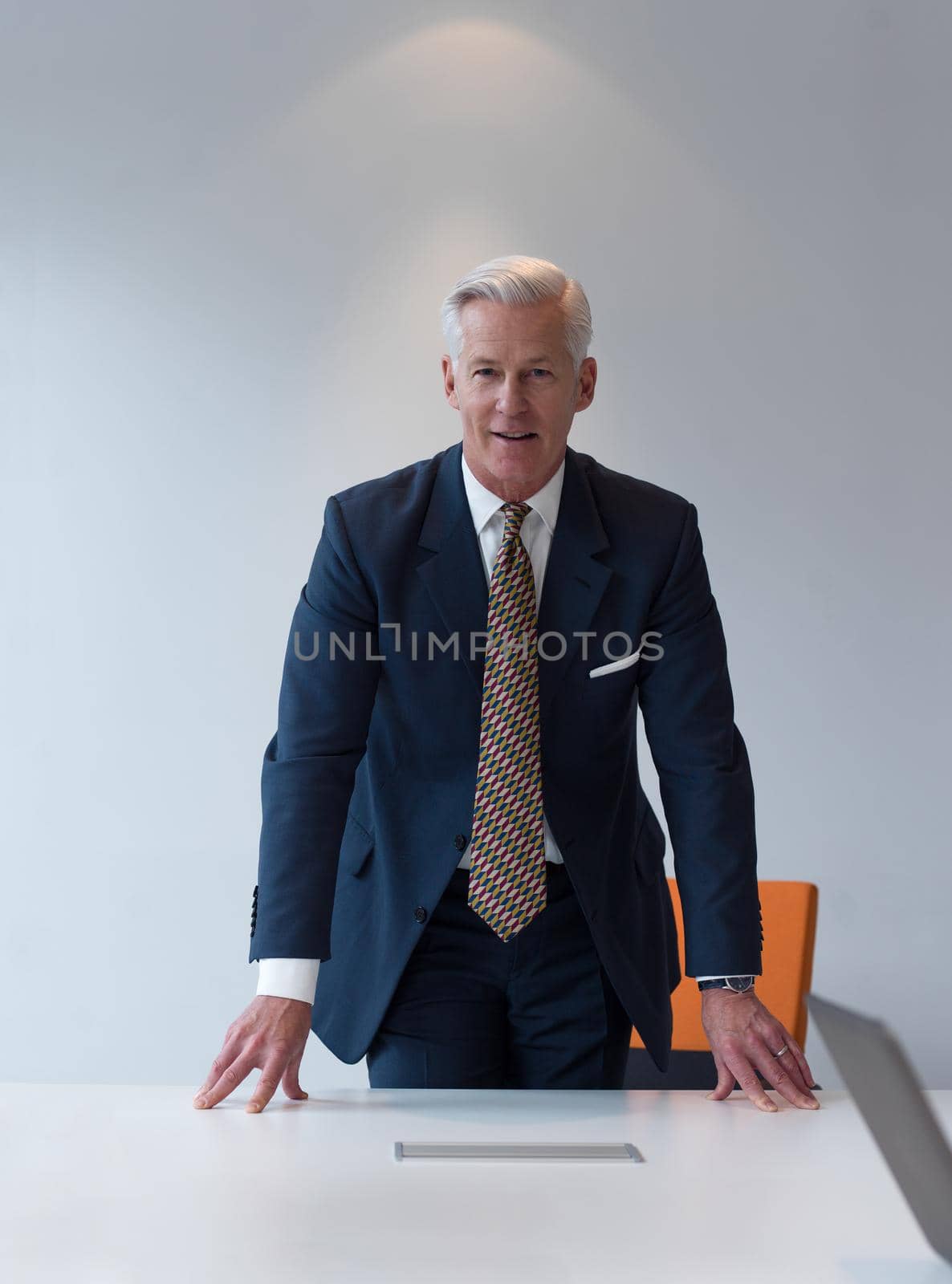 confident and handsome senior business man standing behind table  in meeting room at modern office