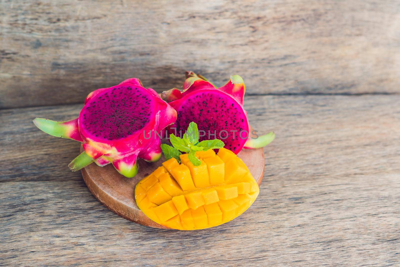 Sliced dragon fruit and mango on an old wooden background by galitskaya