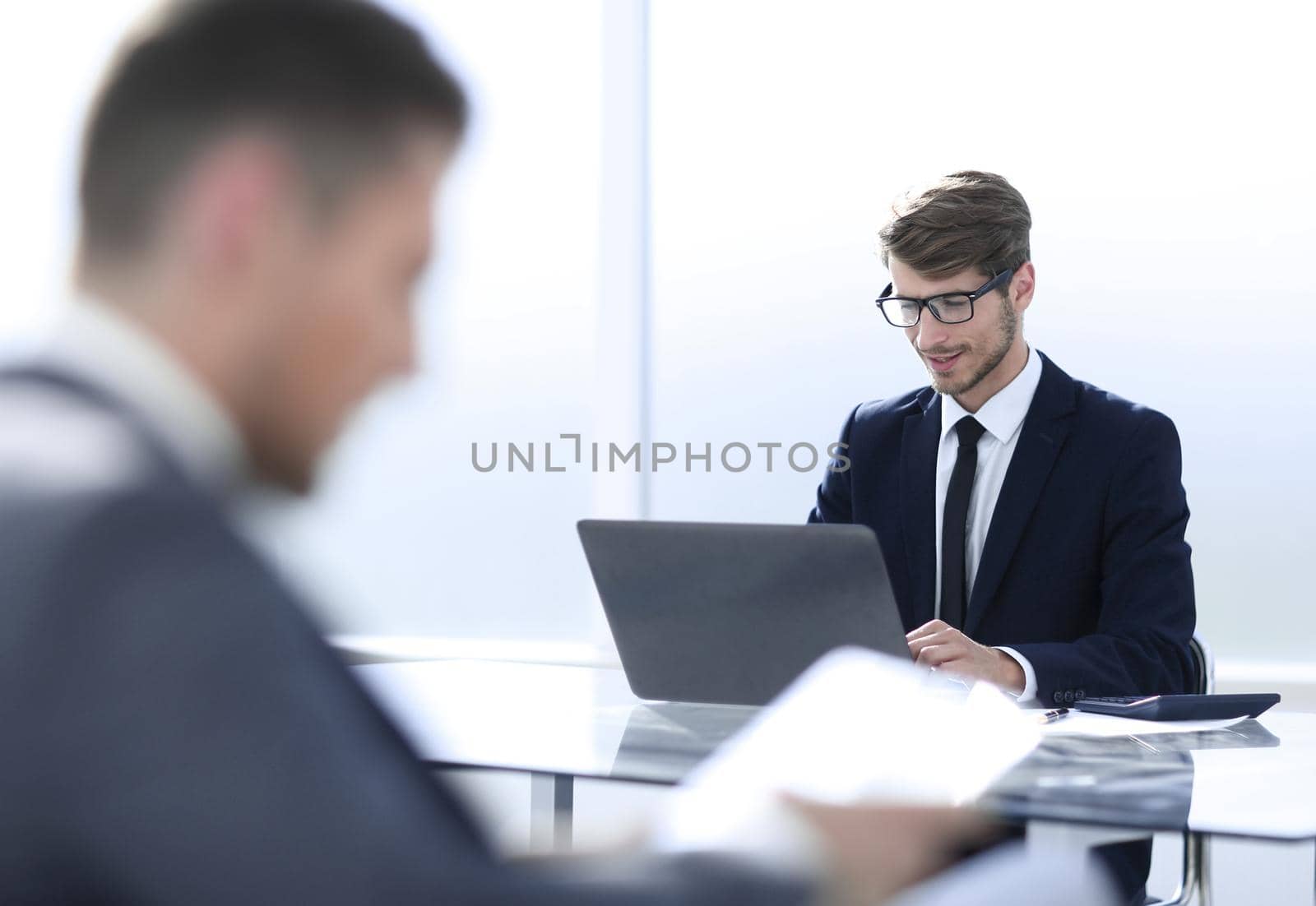 businessman in suit in office using tablet by asdf