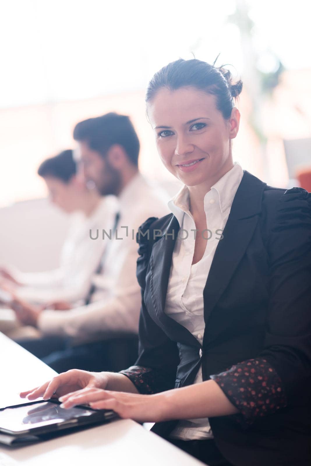 business woman on meeting usineg tablet computer, blured group of people in background at  modern bright startup office interior