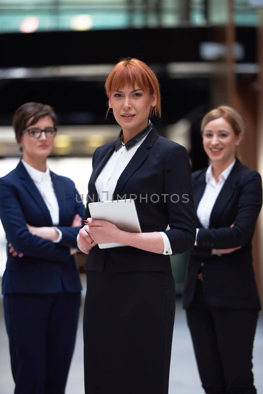 young business woman group,  team standing in modern bright office and working on tablet computer