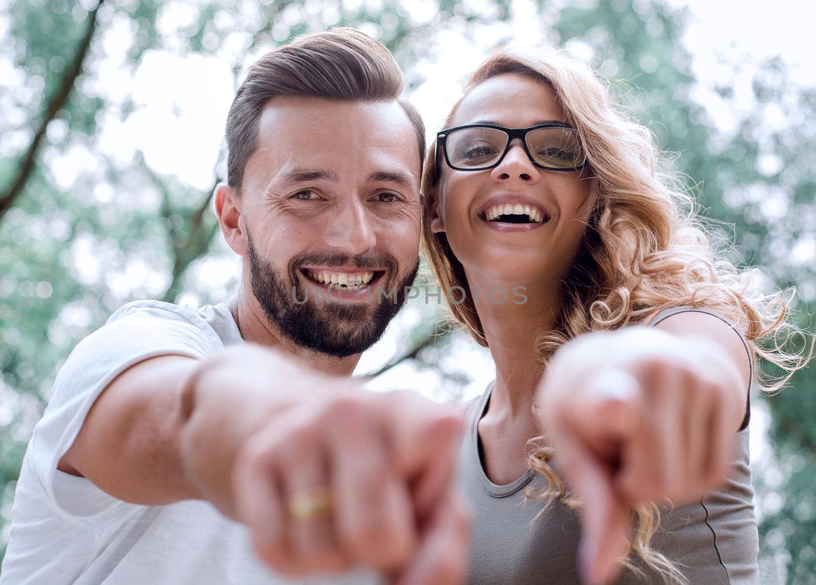 close up.happy newlyweds standing in the Park and pointing at yo by asdf