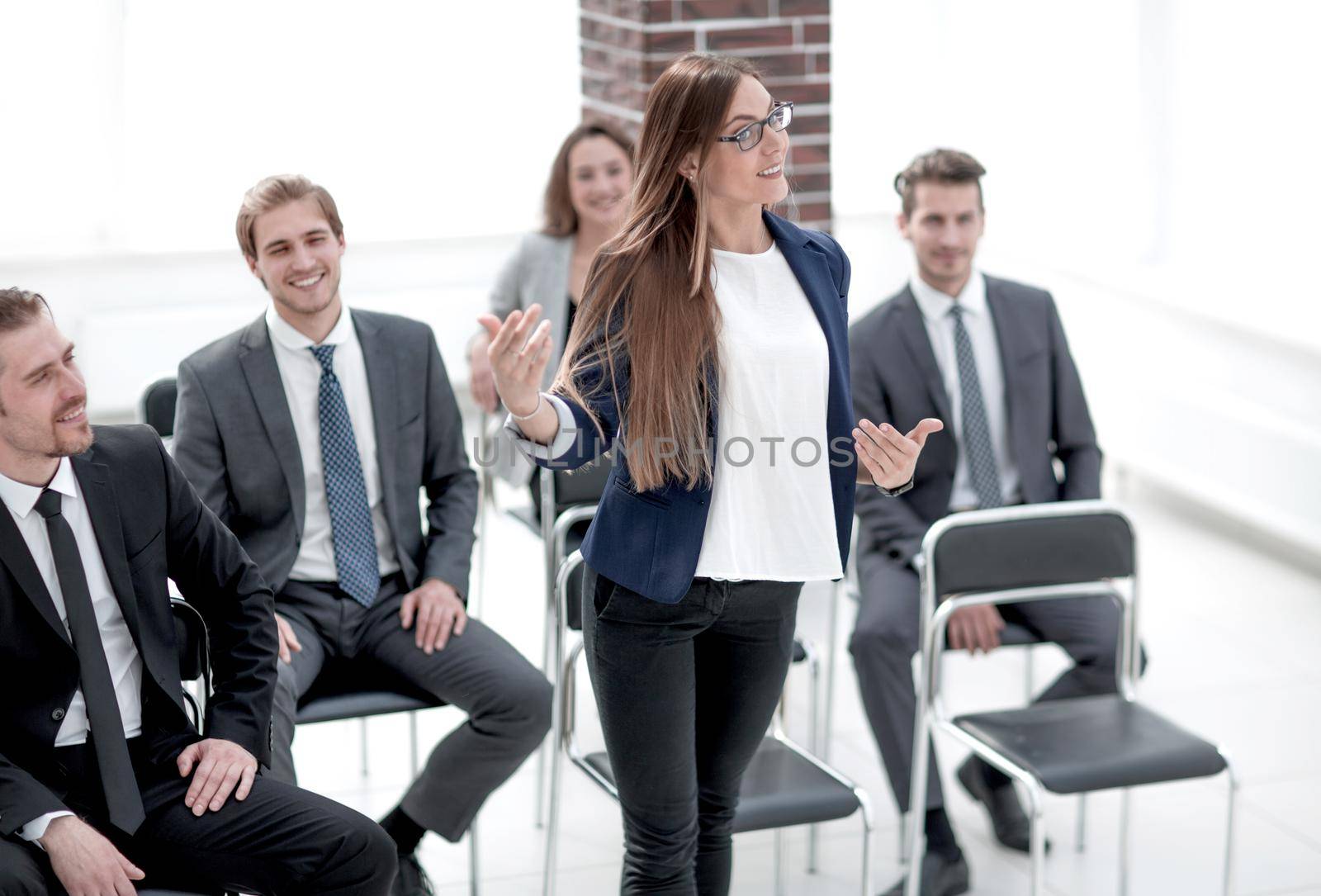Smart businesswoman asking question at seminar with her colleagues near by