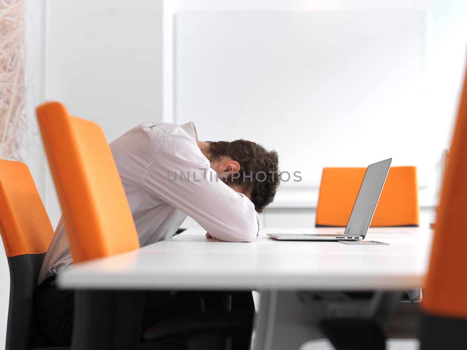 Frustrated young business man have stress problems. Sitting alone at office meeting room  and working on laptop compute.