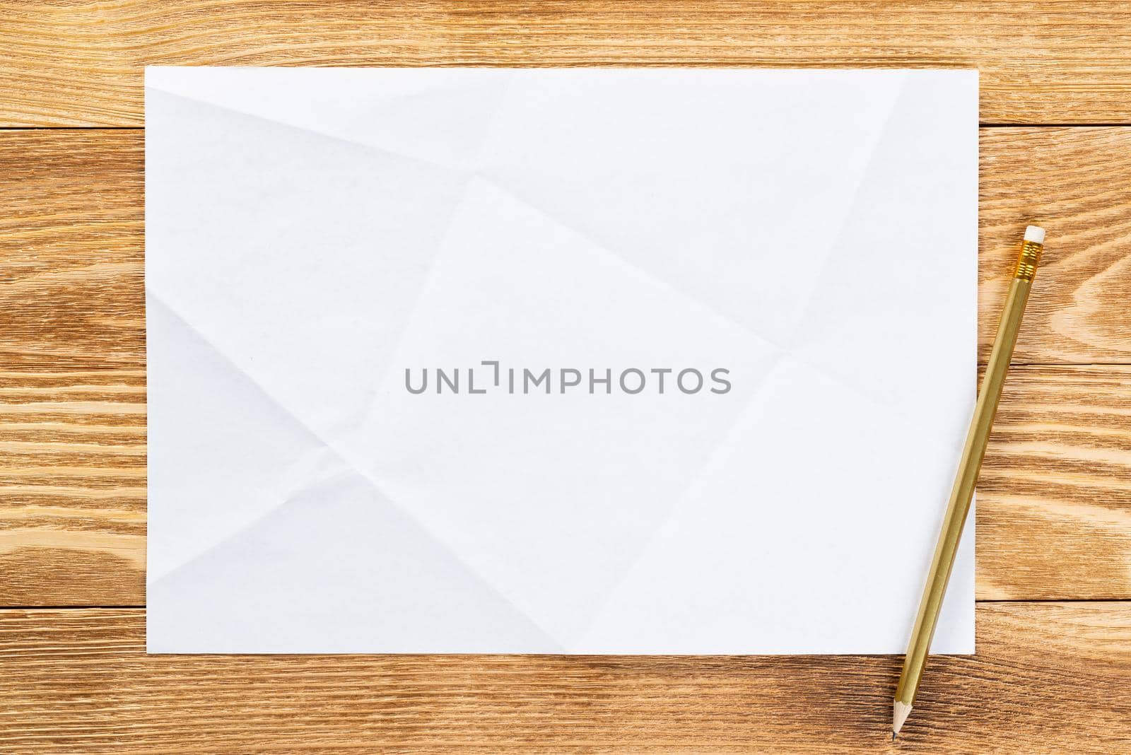 Sheet of paper lying on wooden table. Blank white a4 format paper with pencil. Space for writing and notification. Textured natural wooden background. Vintage copy space for creative design.