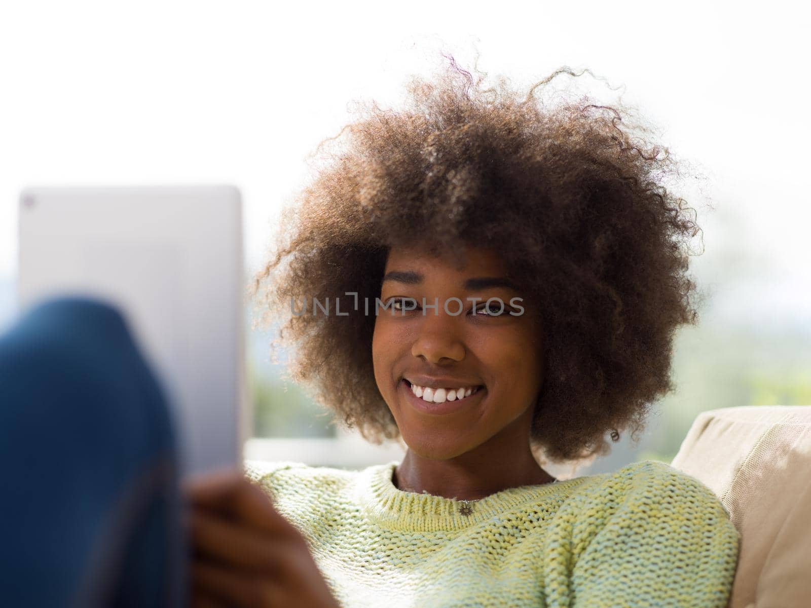 young african american woman at home using digital tablet by dotshock