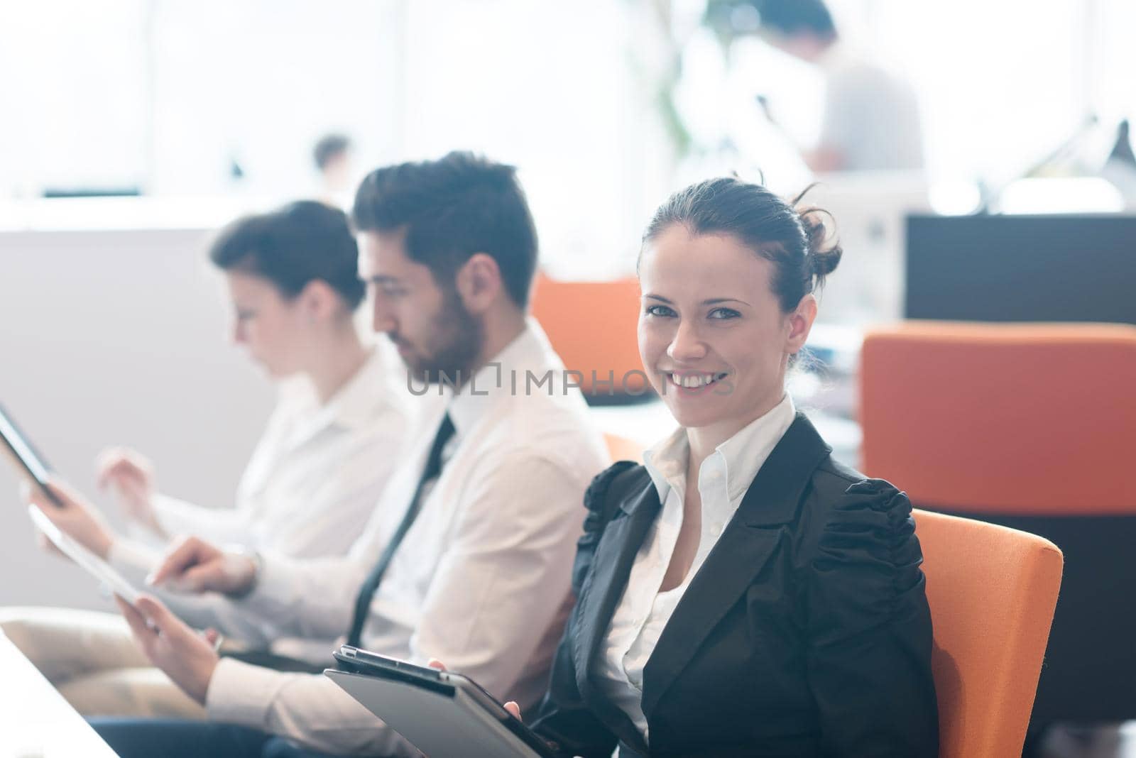 business woman on meeting usineg tablet computer, blured group of people in background at  modern bright startup office interior