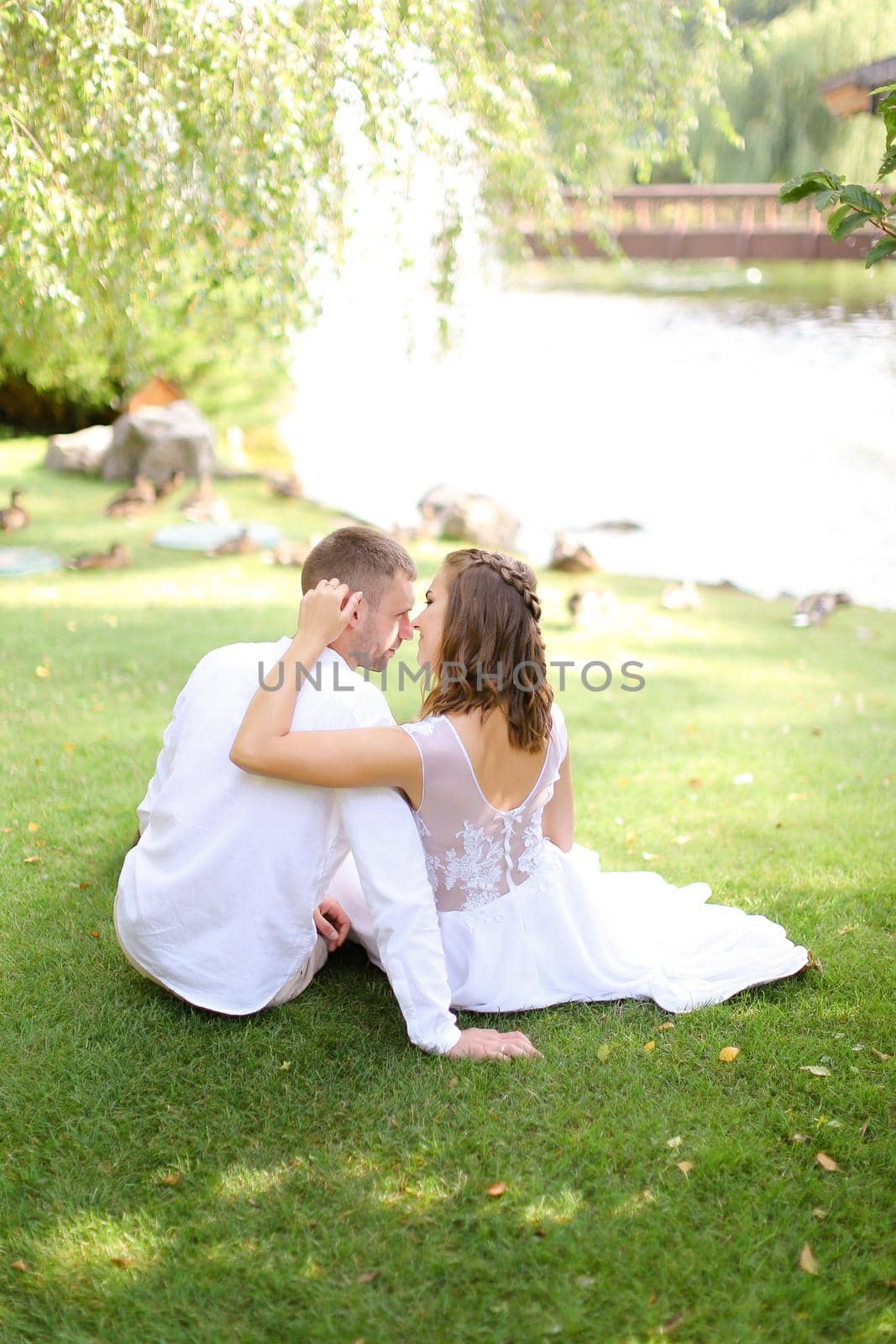 Young caucasian couple sittling near lake on grass. by sisterspro