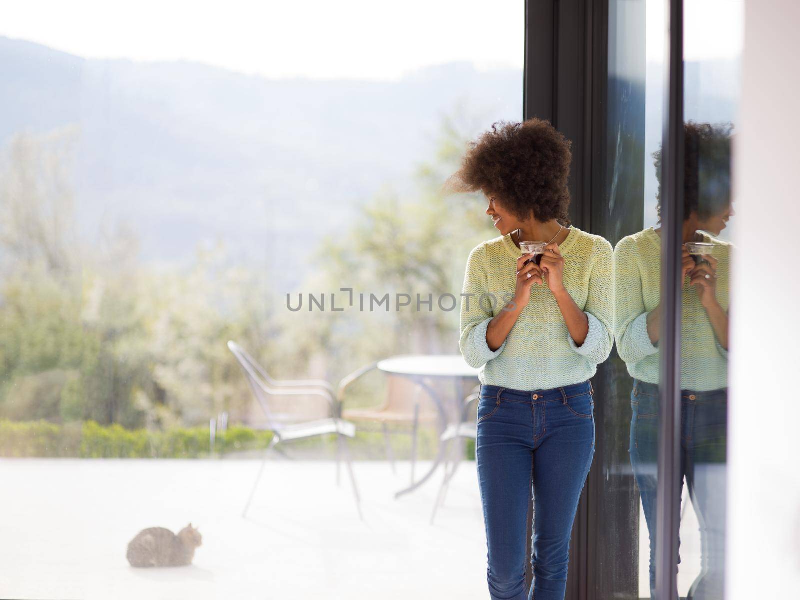 African American woman drinking coffee looking out the window by dotshock