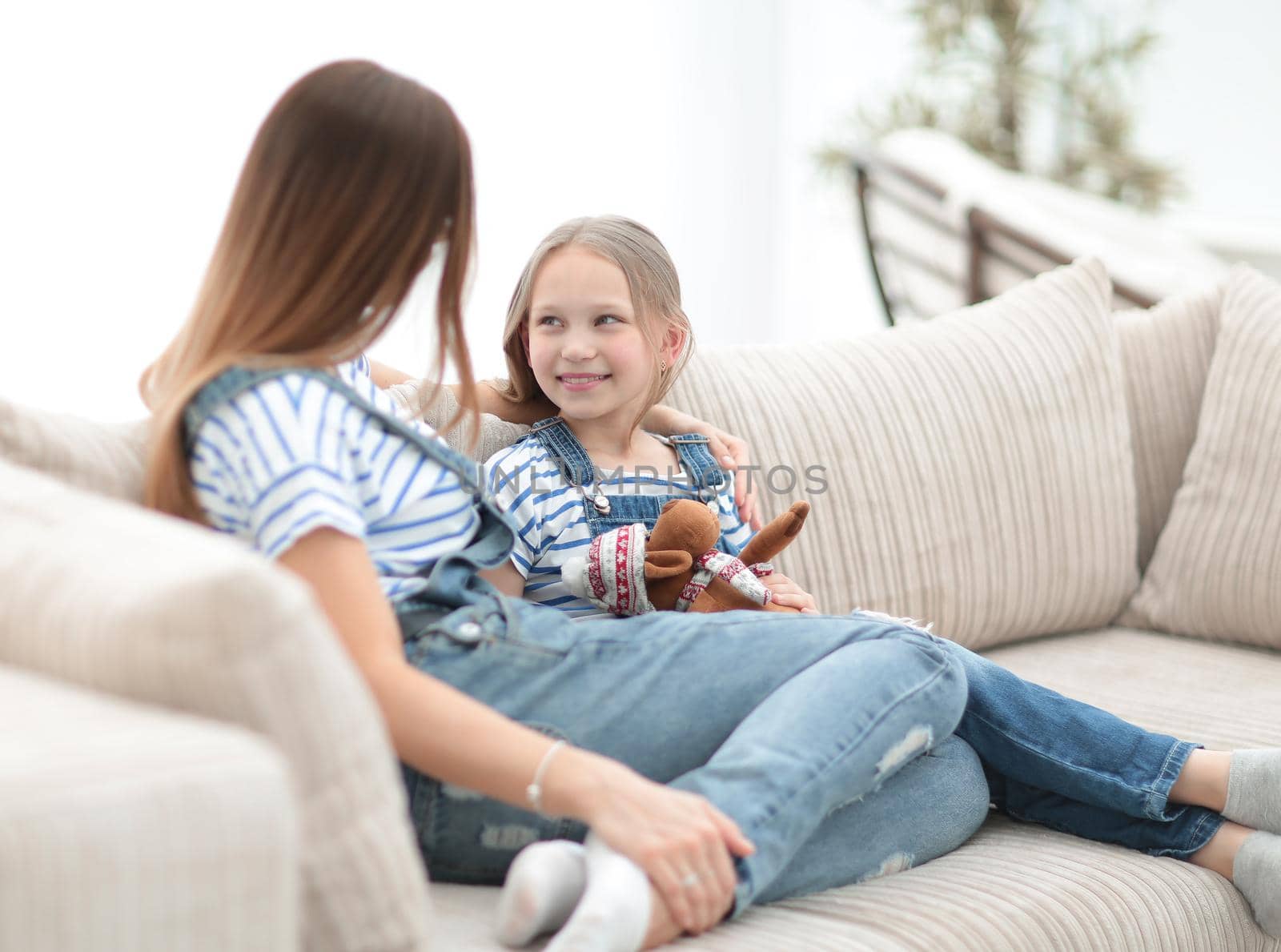 mom and little daughter sitting on the couch in a cozy living room.photo with copy space
