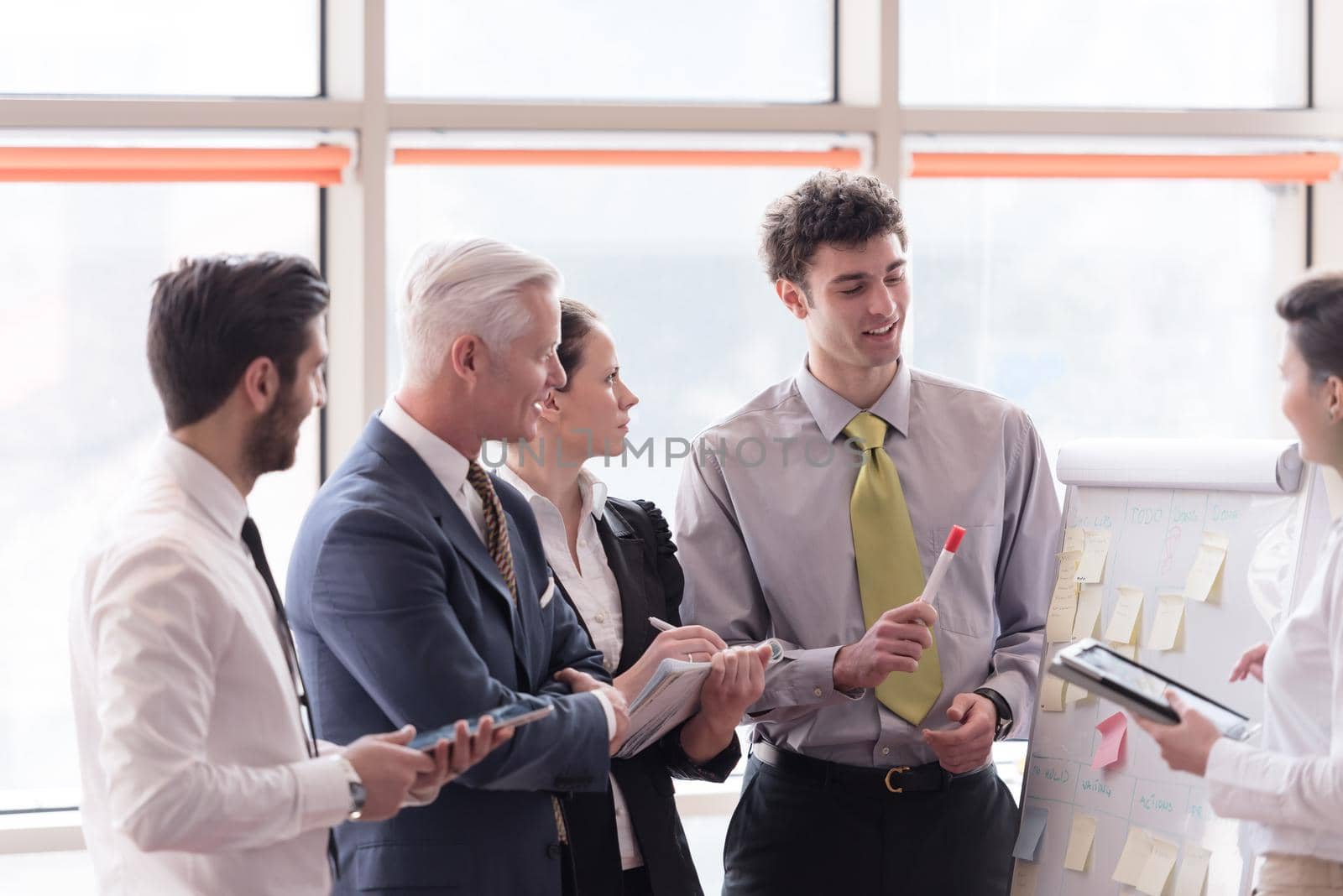 young startup businessman making presentation of project to senior investior, group of business people taking notes and make plans on white  flip board and tablet computer