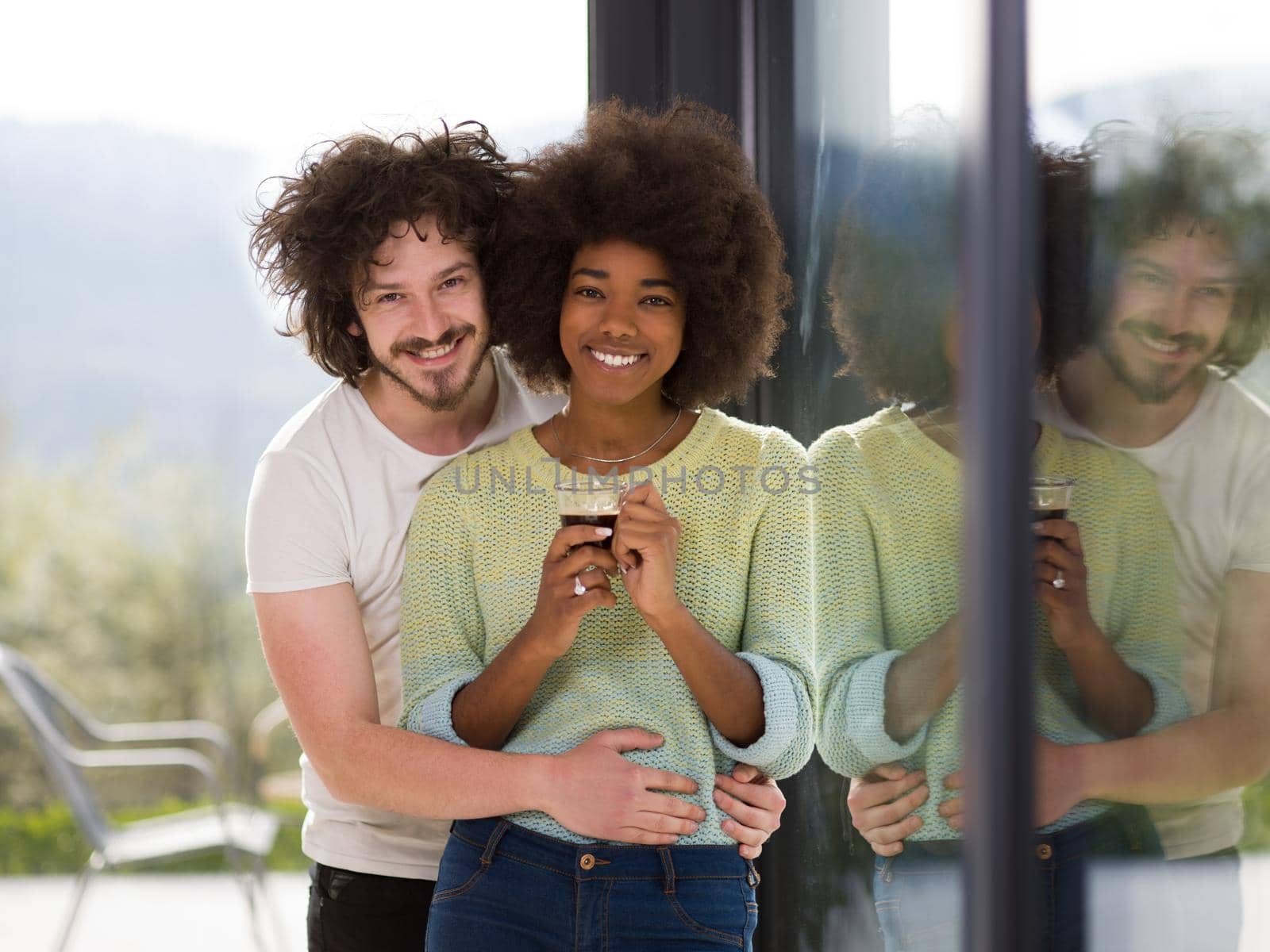 romantic happy young multiethnic couple enjoying morning coffee by the window in their luxury home