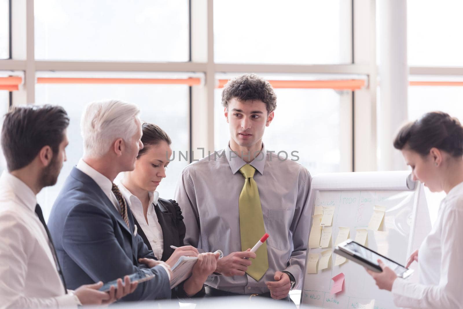 young startup businessman making presentation of project to senior investior, group of business people taking notes and make plans on white  flip board and tablet computer