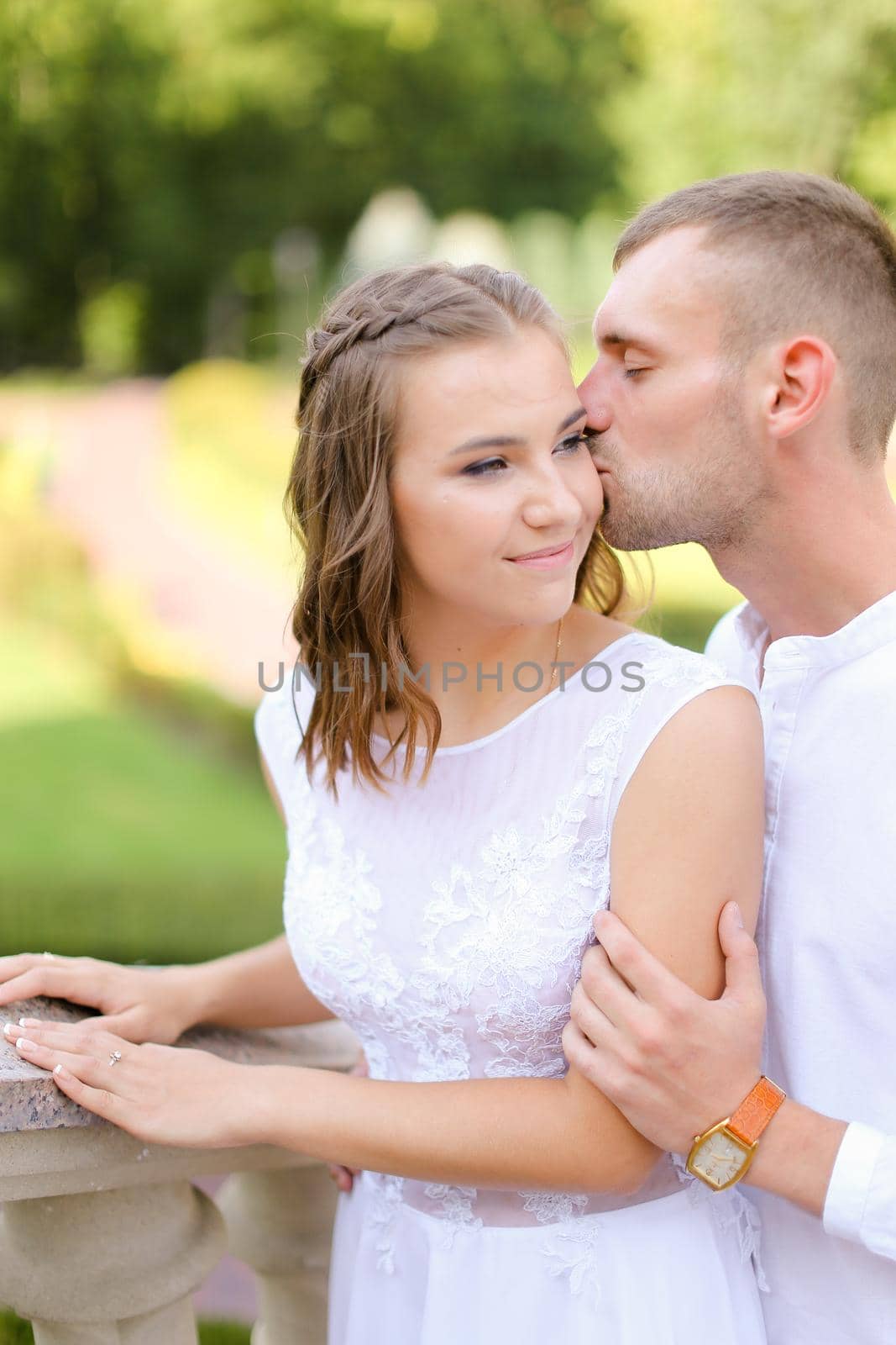 Happy groom kissing bride outside. Concept of bridal photo session adn wedding, relationship and feelings.