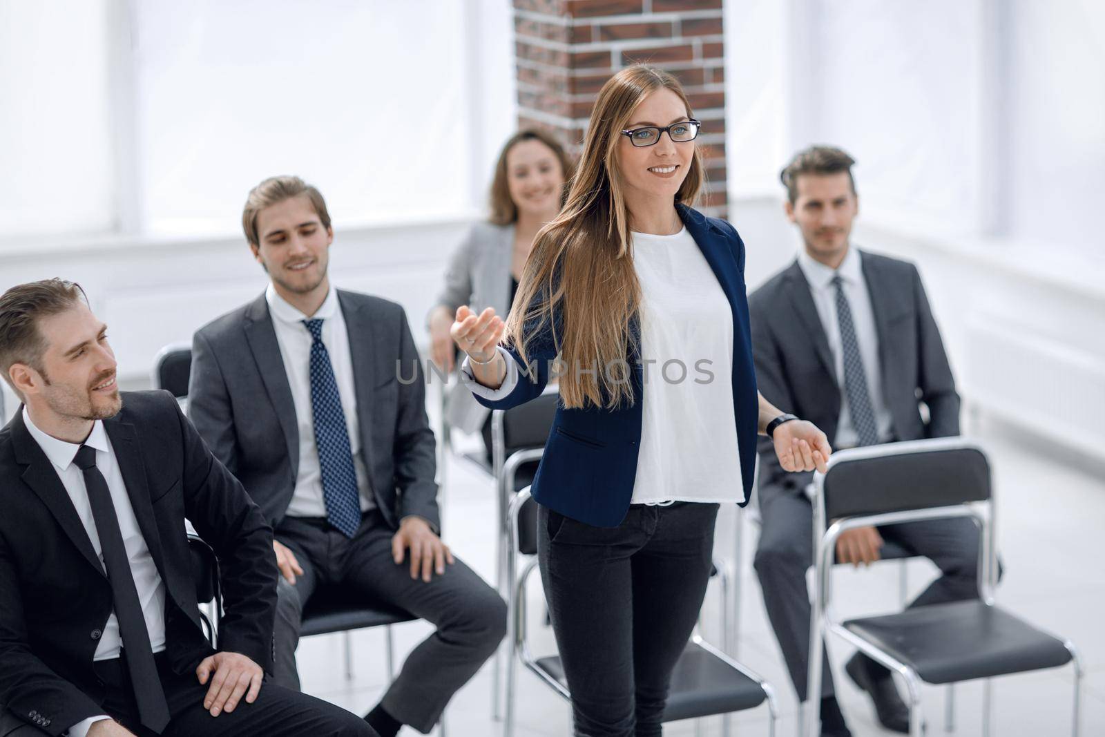 Smart businesswoman asking question at seminar with her colleagues near by