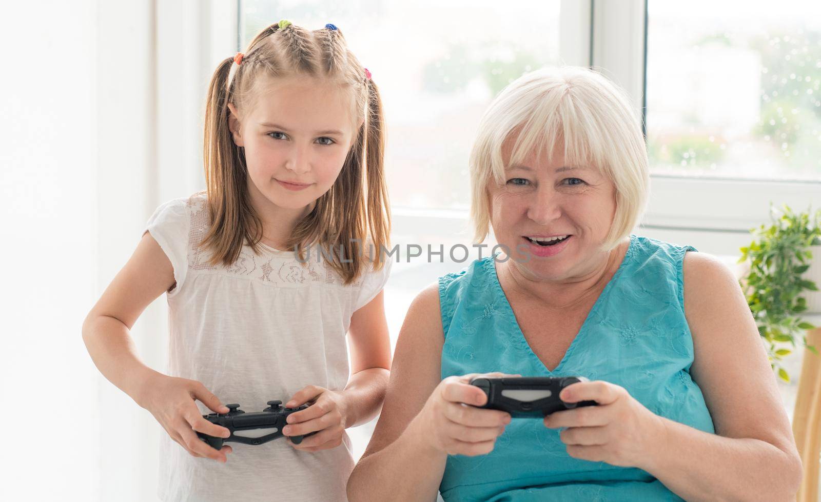 Woman playing video game with granddaughter by GekaSkr