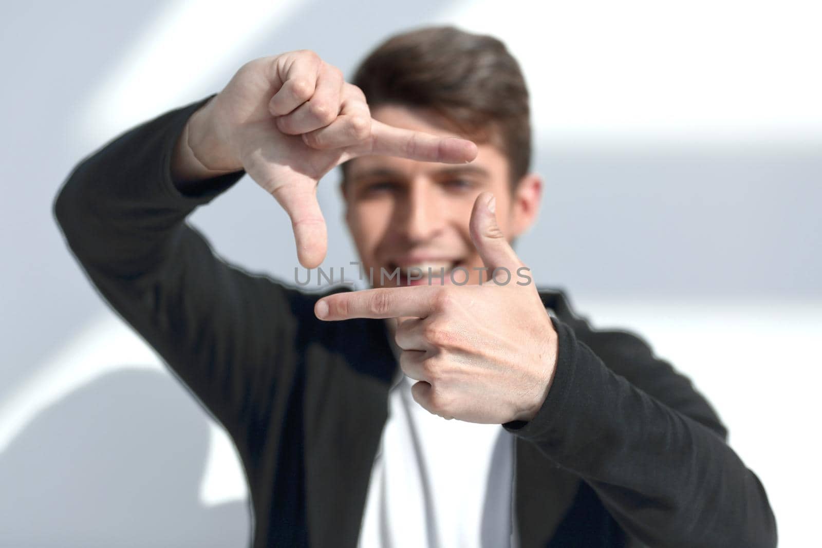 modern guy looks into the frame formed by his hands.photo on light background