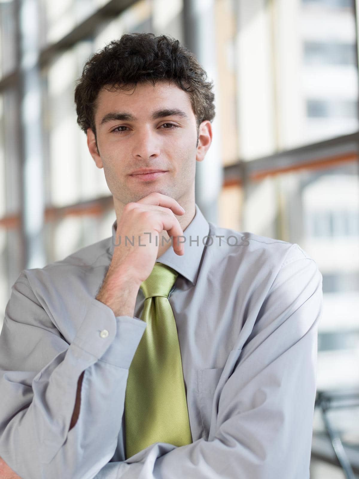 portrait of young business man at modern office  interior with big windows in background