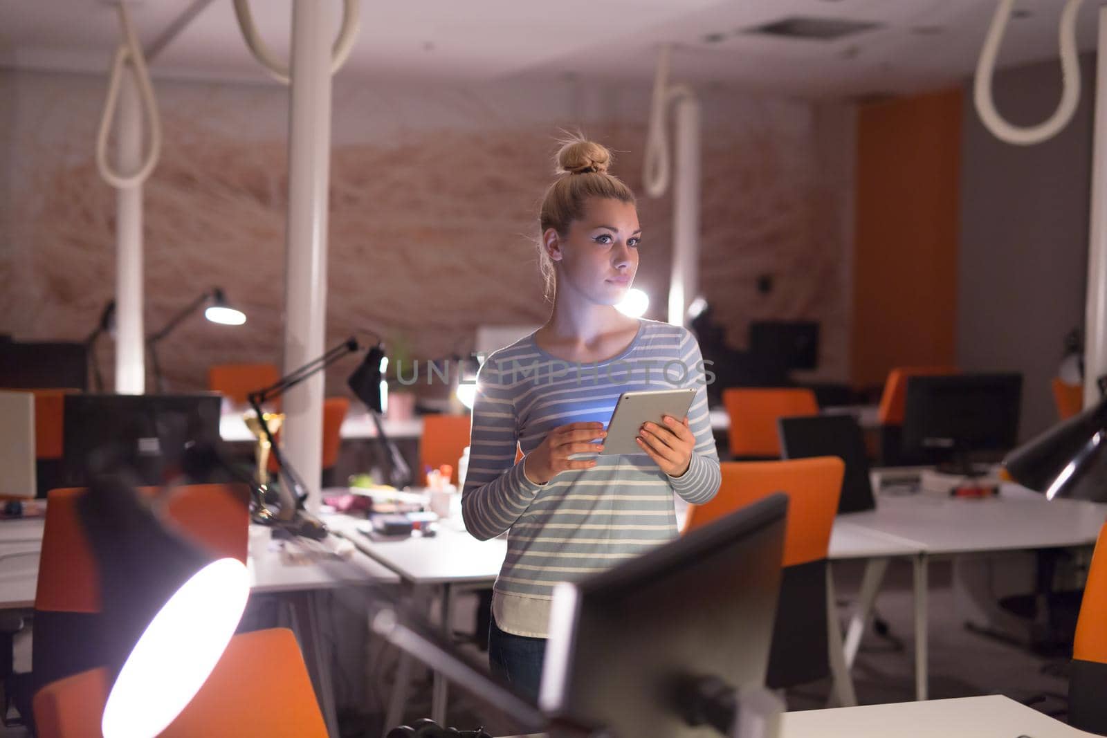 woman working on digital tablet in night office by dotshock