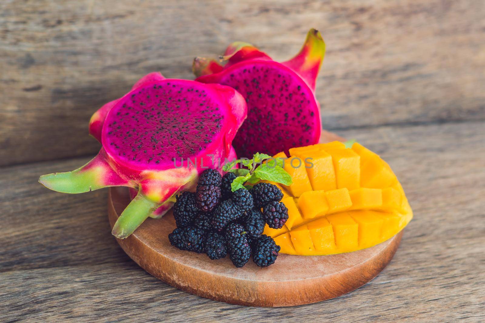 Sliced dragon fruit and mango on an old wooden background.