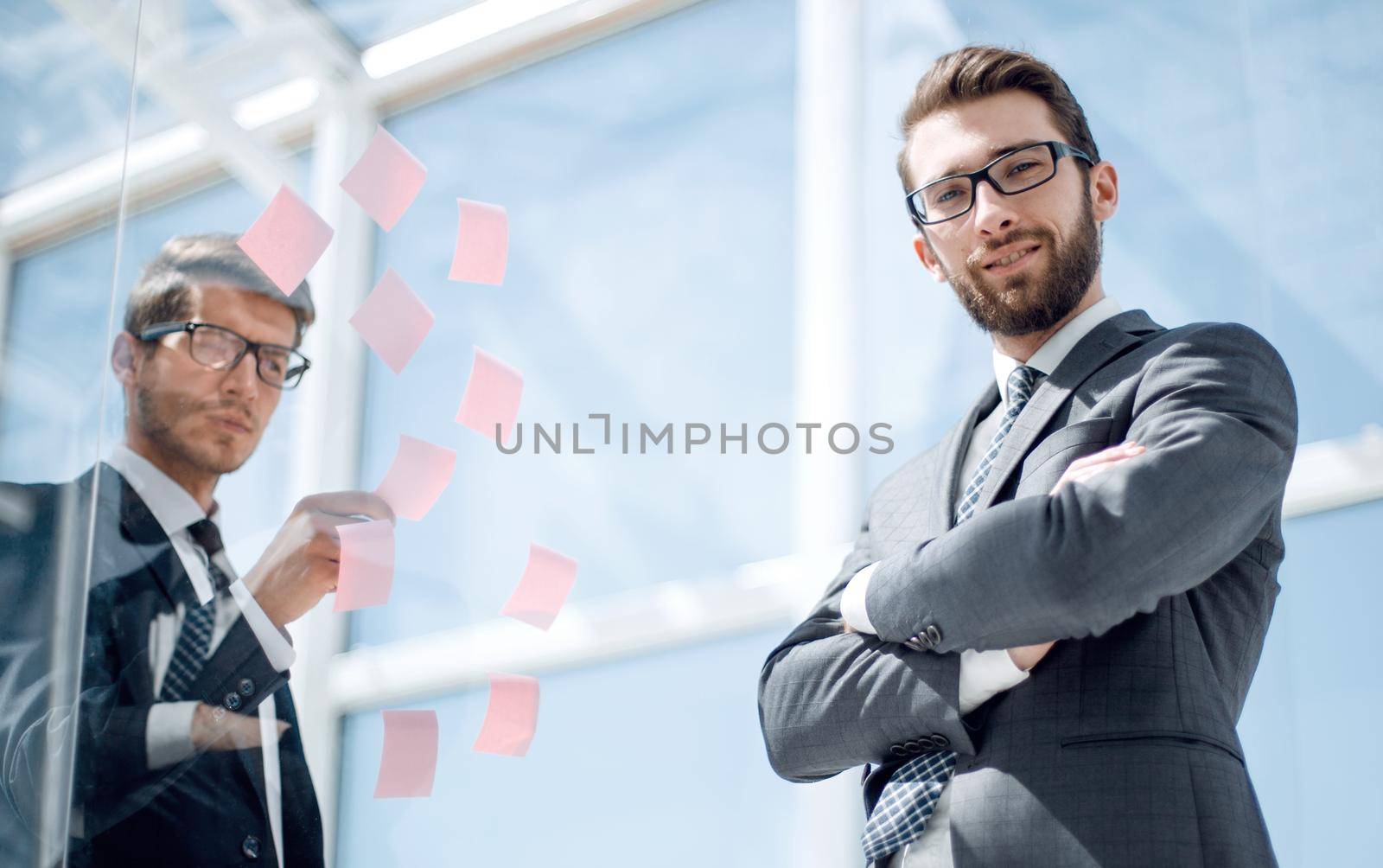 Manager and employee standing near a transparent Board in the office by asdf