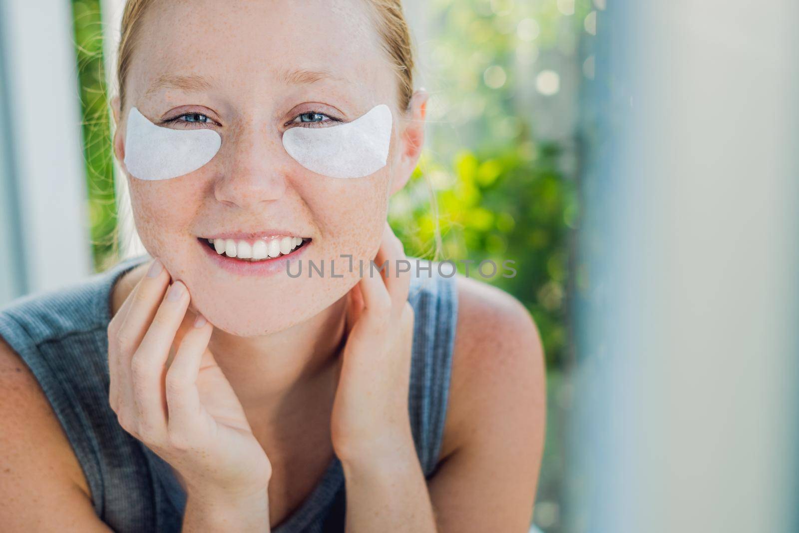 Portrait of Beauty Red-haired woman with eye patches showing an effect of perfect skin. Spa Girl.