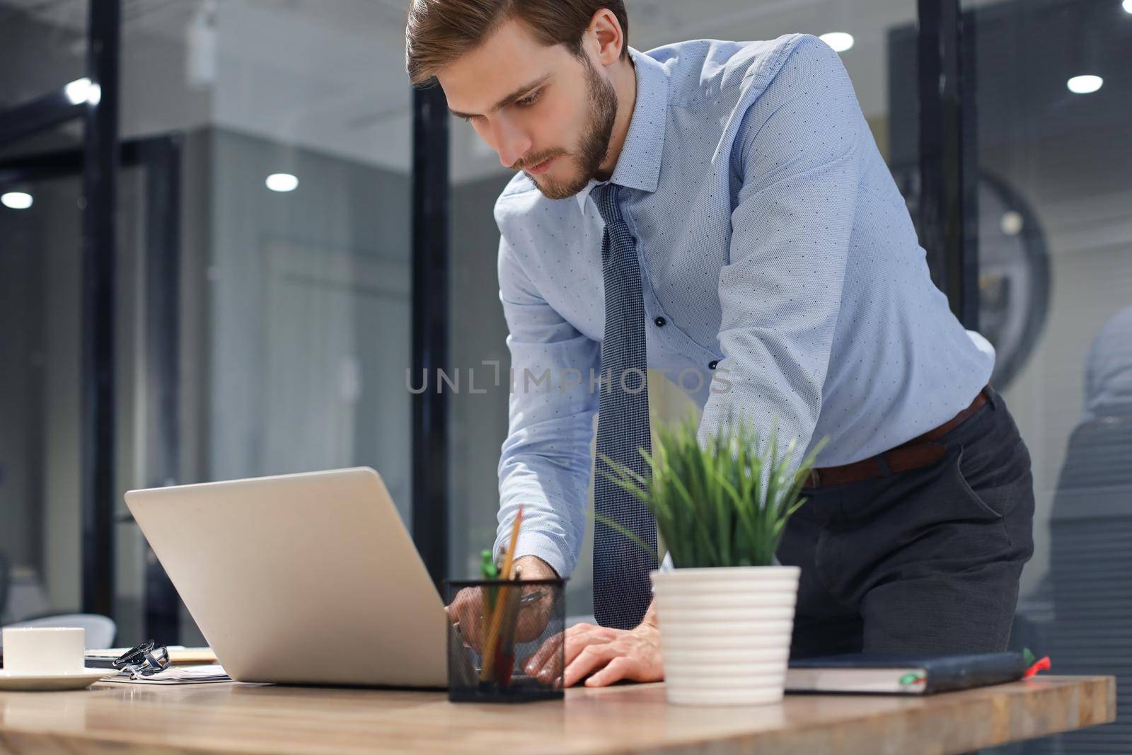 Young modern business man analyzing data using laptop while working in the office