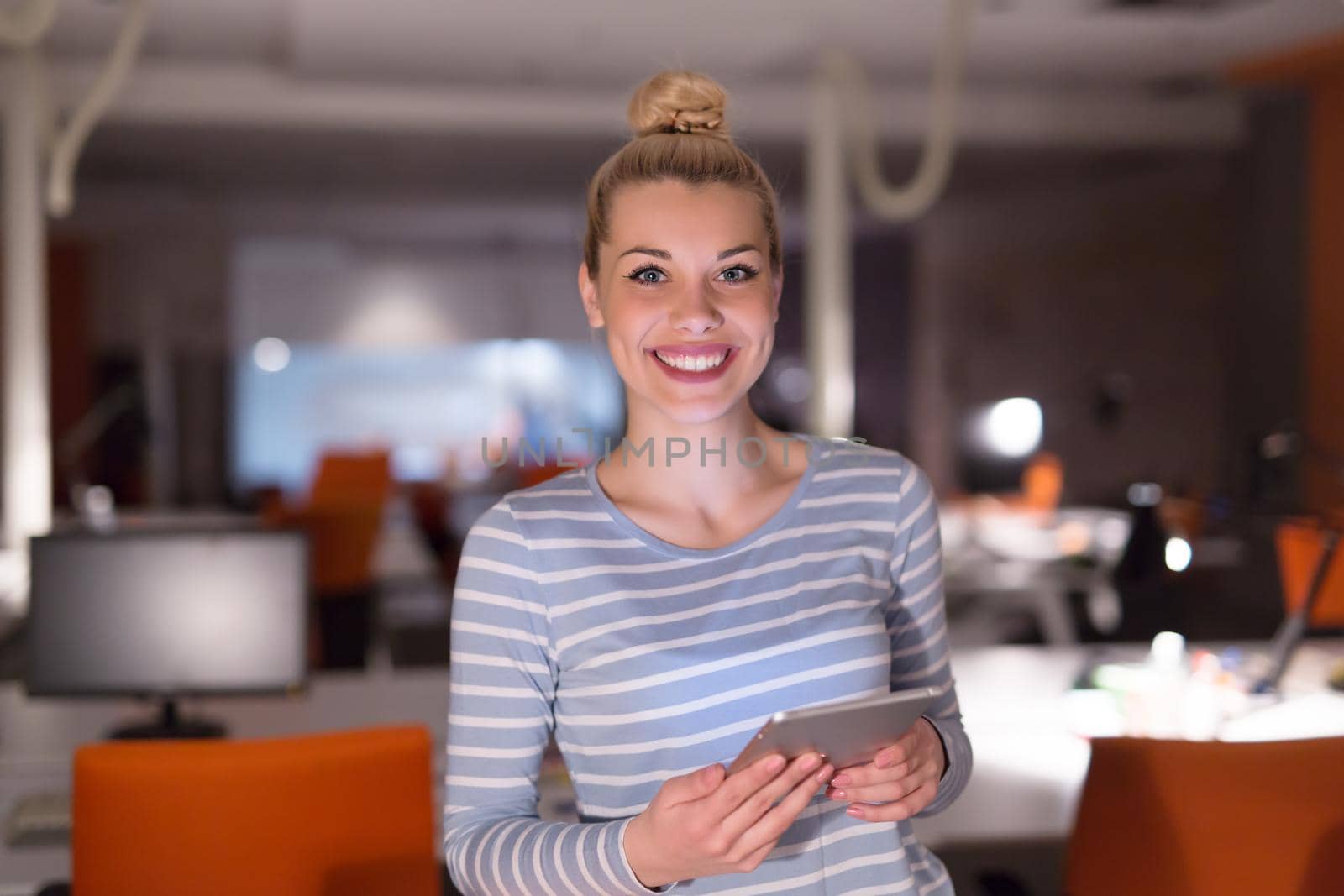 woman working on digital tablet in night office by dotshock