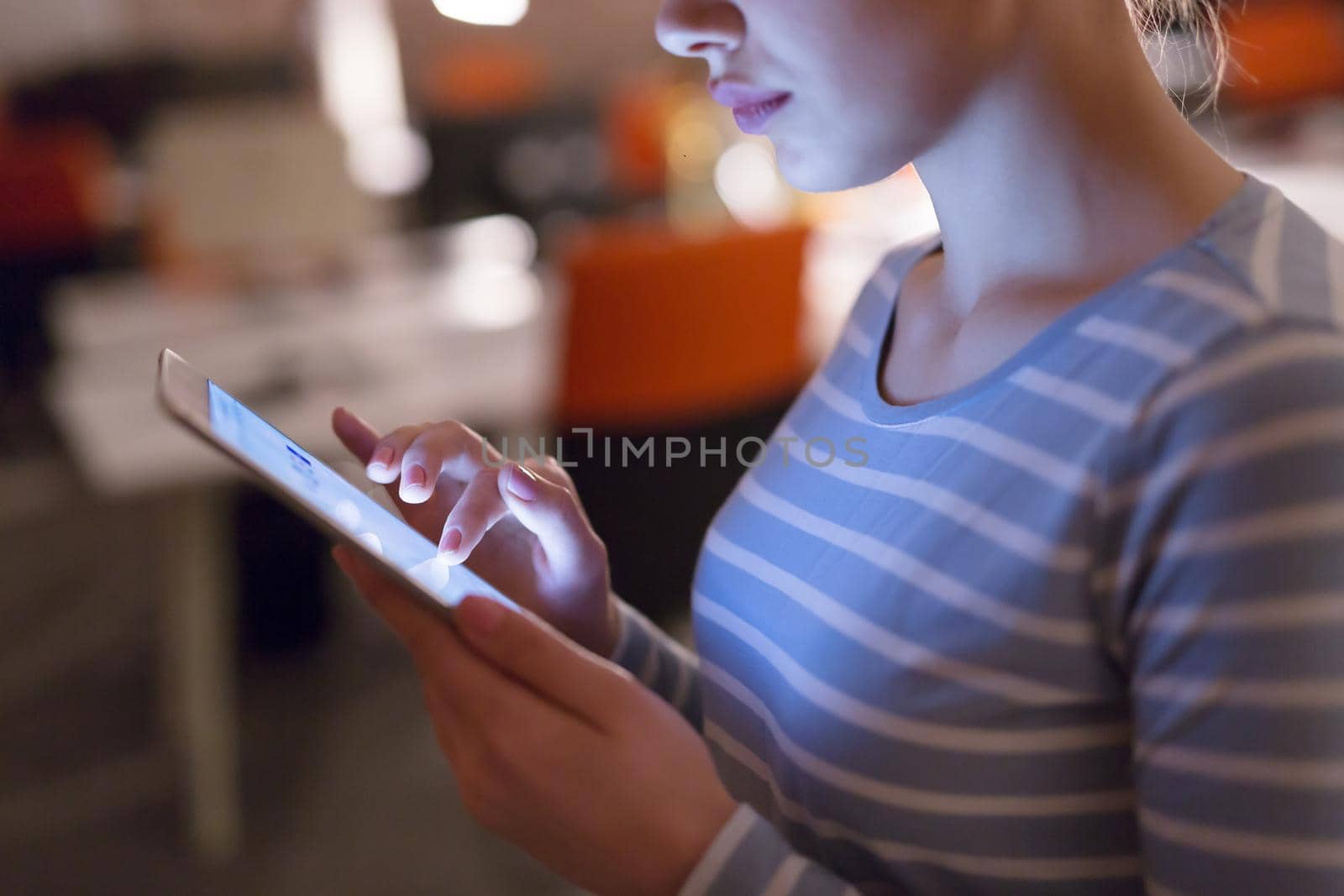 woman working on digital tablet in night office by dotshock