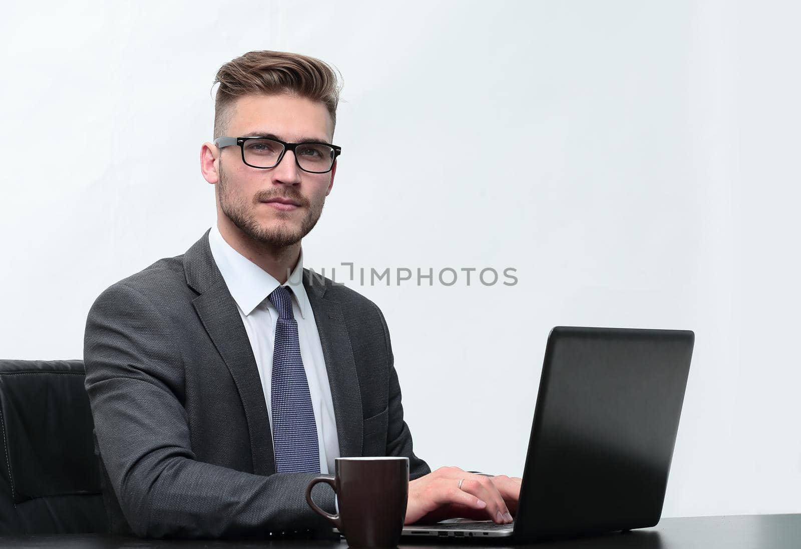 serious businessman with a Cup of coffee sitting at his Desk by asdf