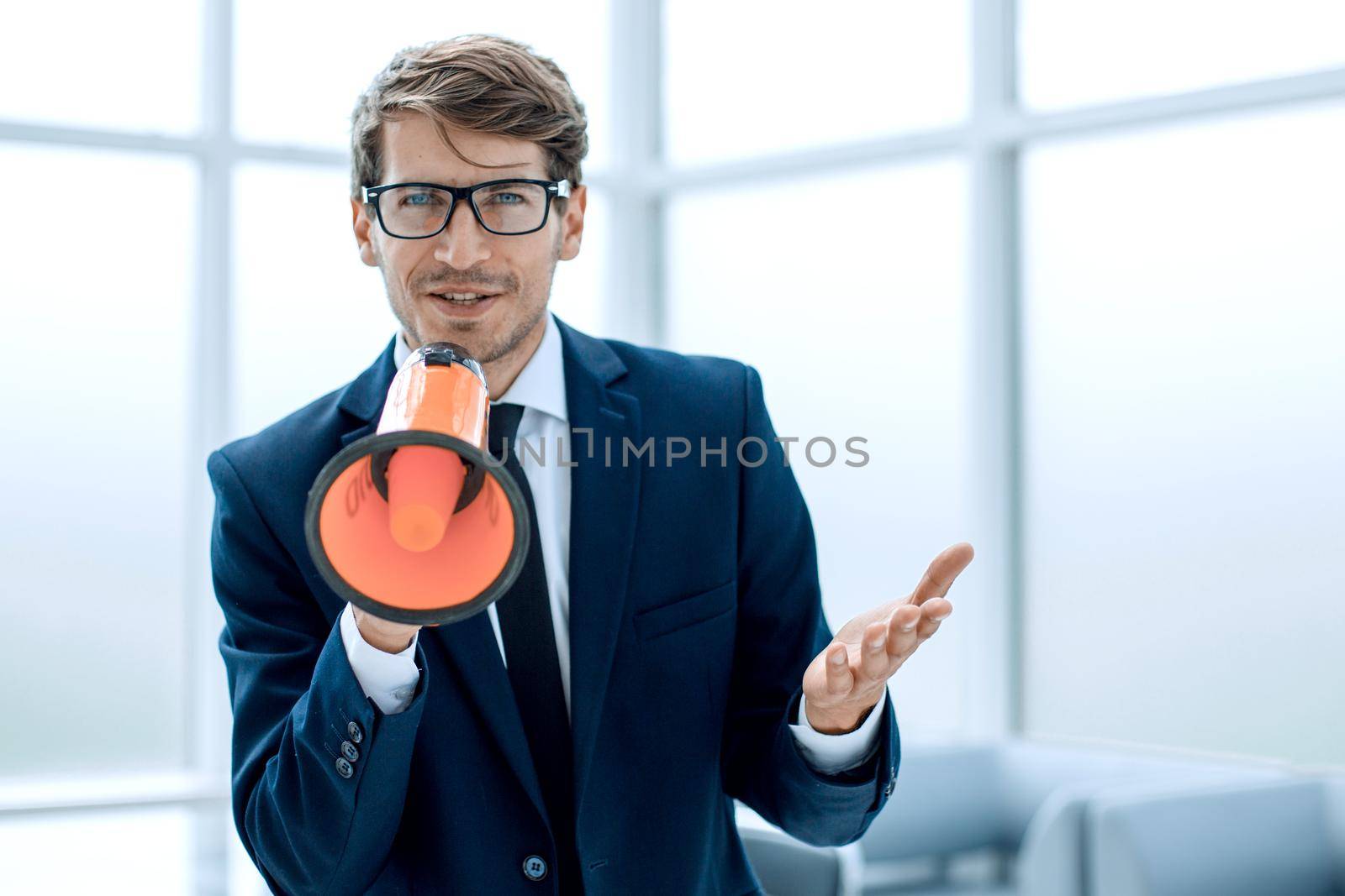 responsible businessman with a megaphone standing in the office.the concept of management