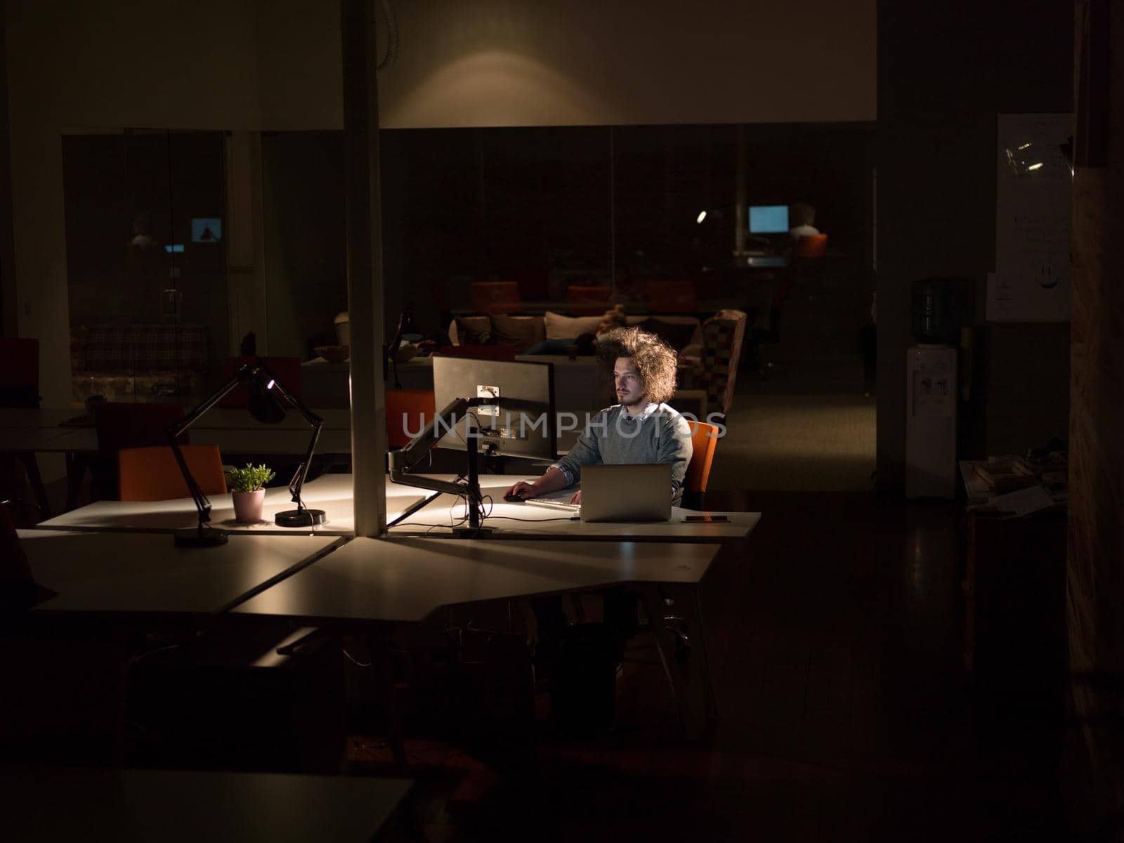 man working on computer in dark office by dotshock