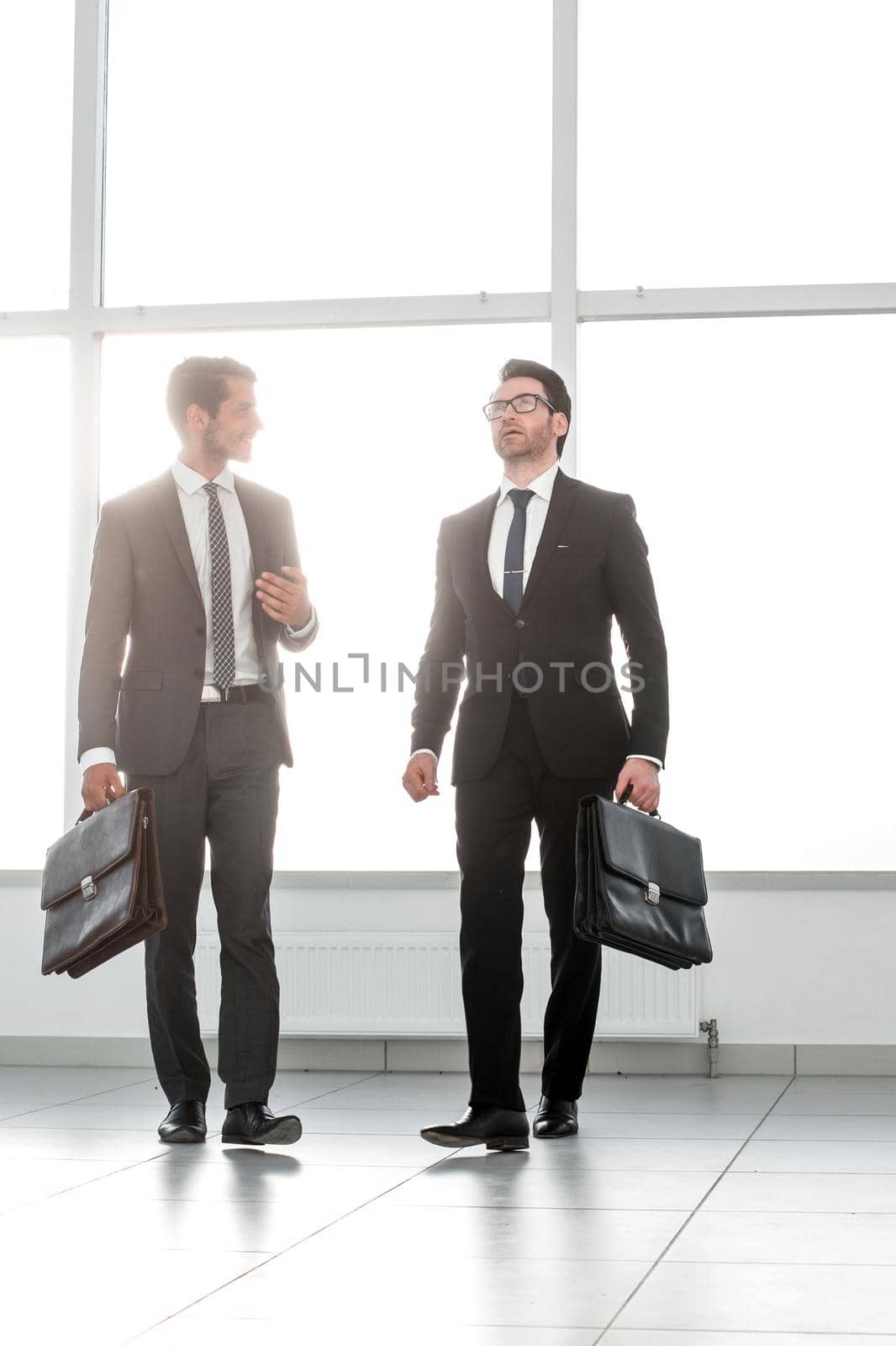 far away. two businessmen are walking in the lobby of the office by asdf