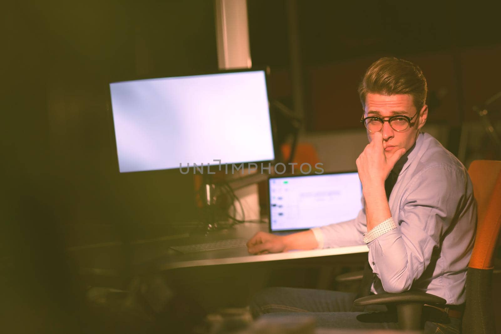 man working on computer in dark office by dotshock