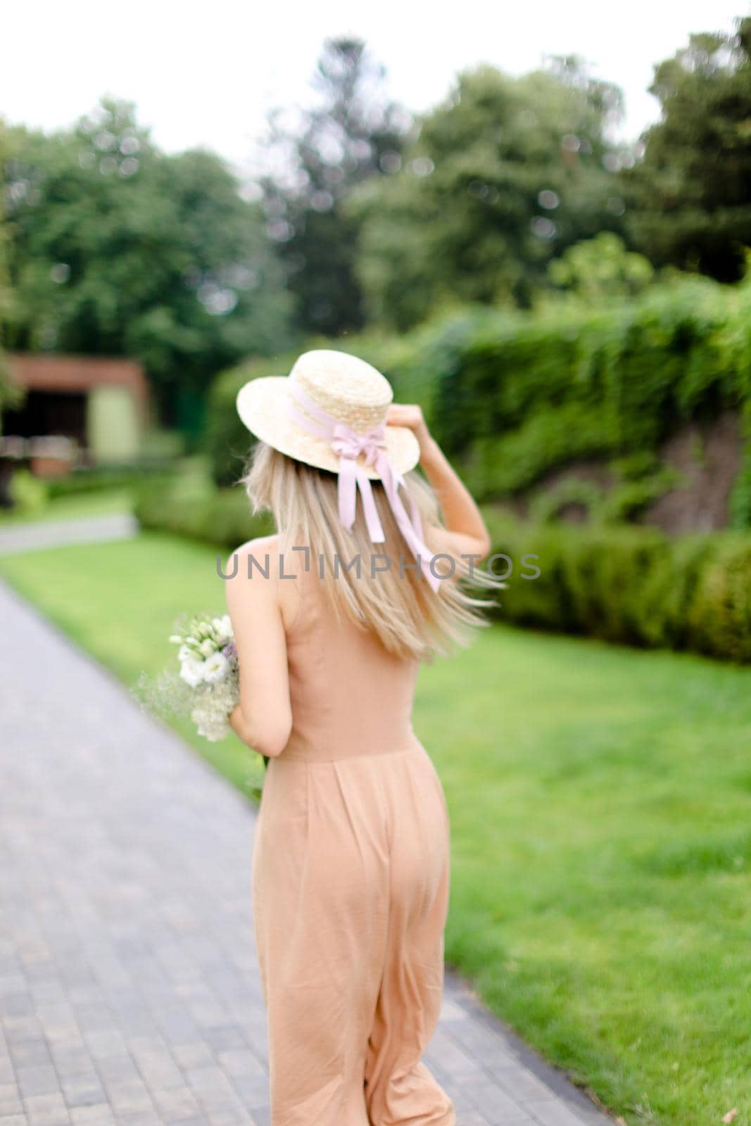 Back view of young blonde woman in body color overalls and hat. by sisterspro