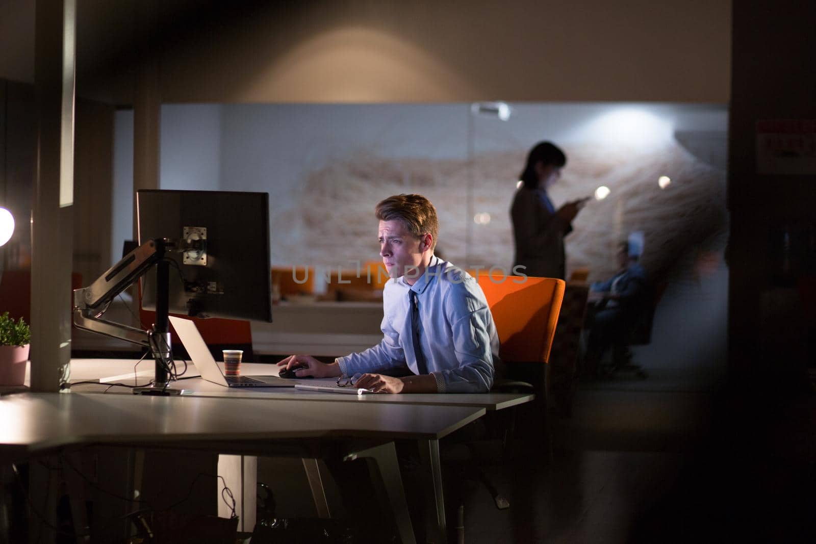 Young man working on computer at night in dark office. The designer works in the later time.