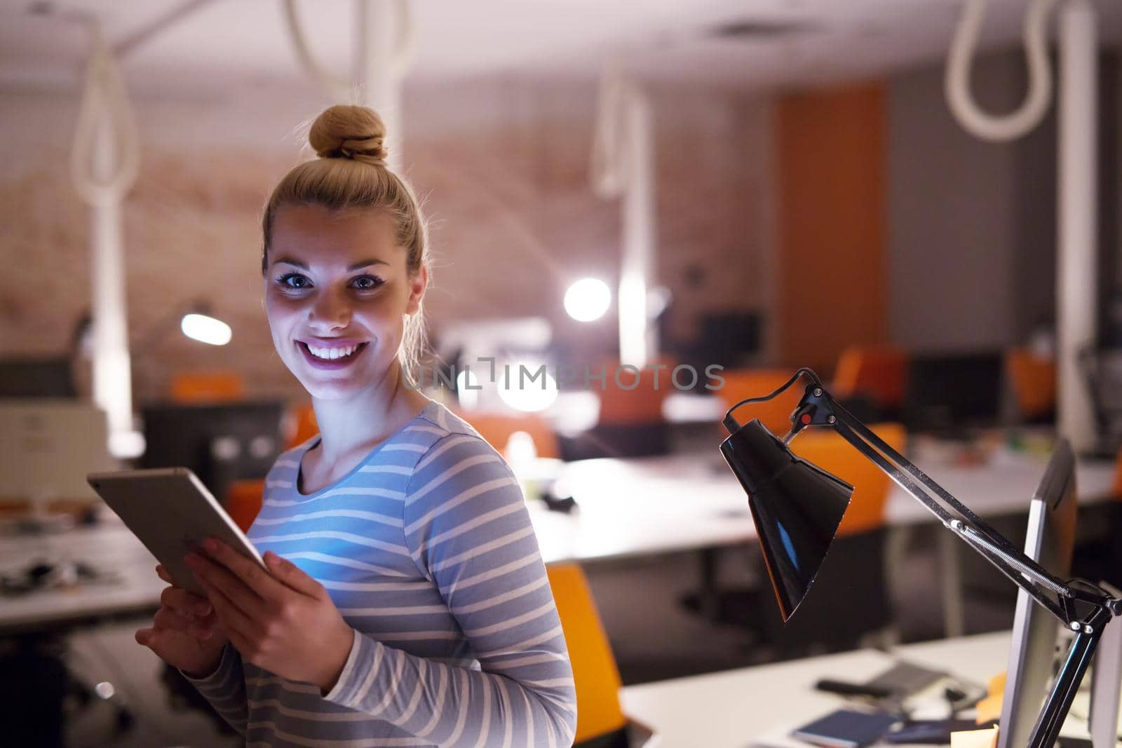 woman working on digital tablet in night office by dotshock